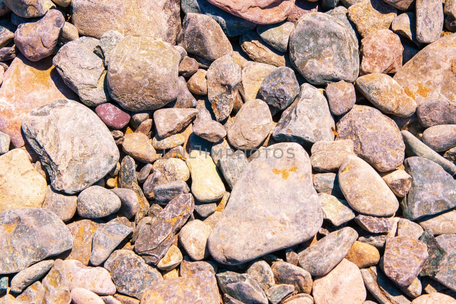 Stone texture background. Close-up of natural sea gravel or pebbles at summer beach with selective focus. Natural design backdrop for your project.