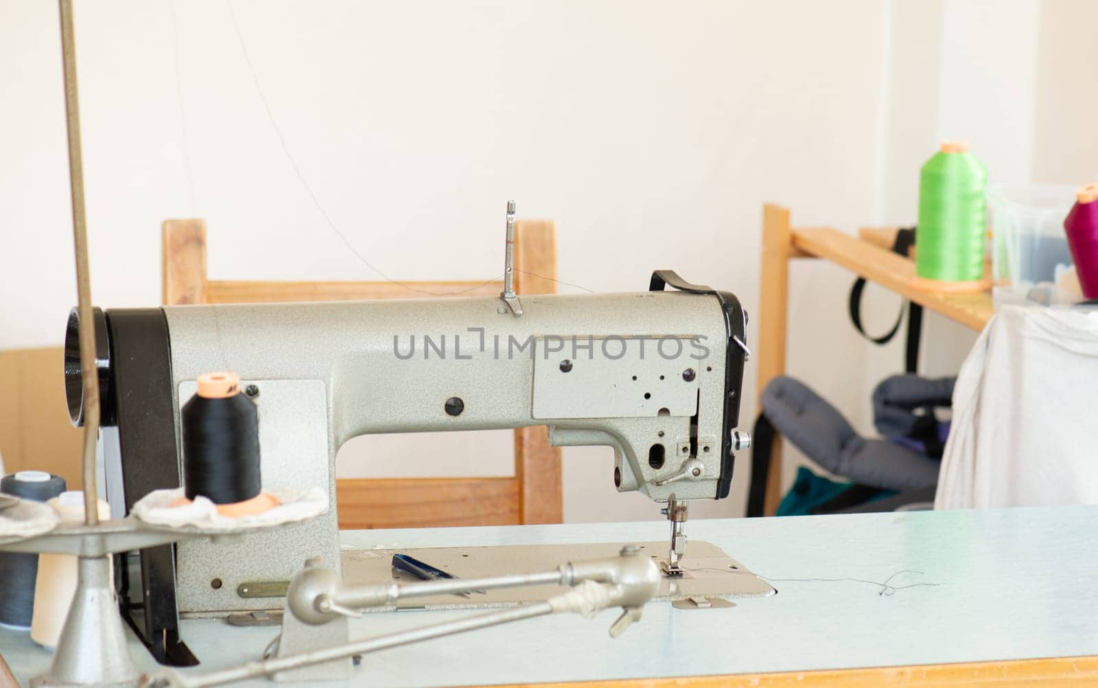 Industrial sewing machine with colorful thread, working place, manufacture for clothes, handmade, small local business
