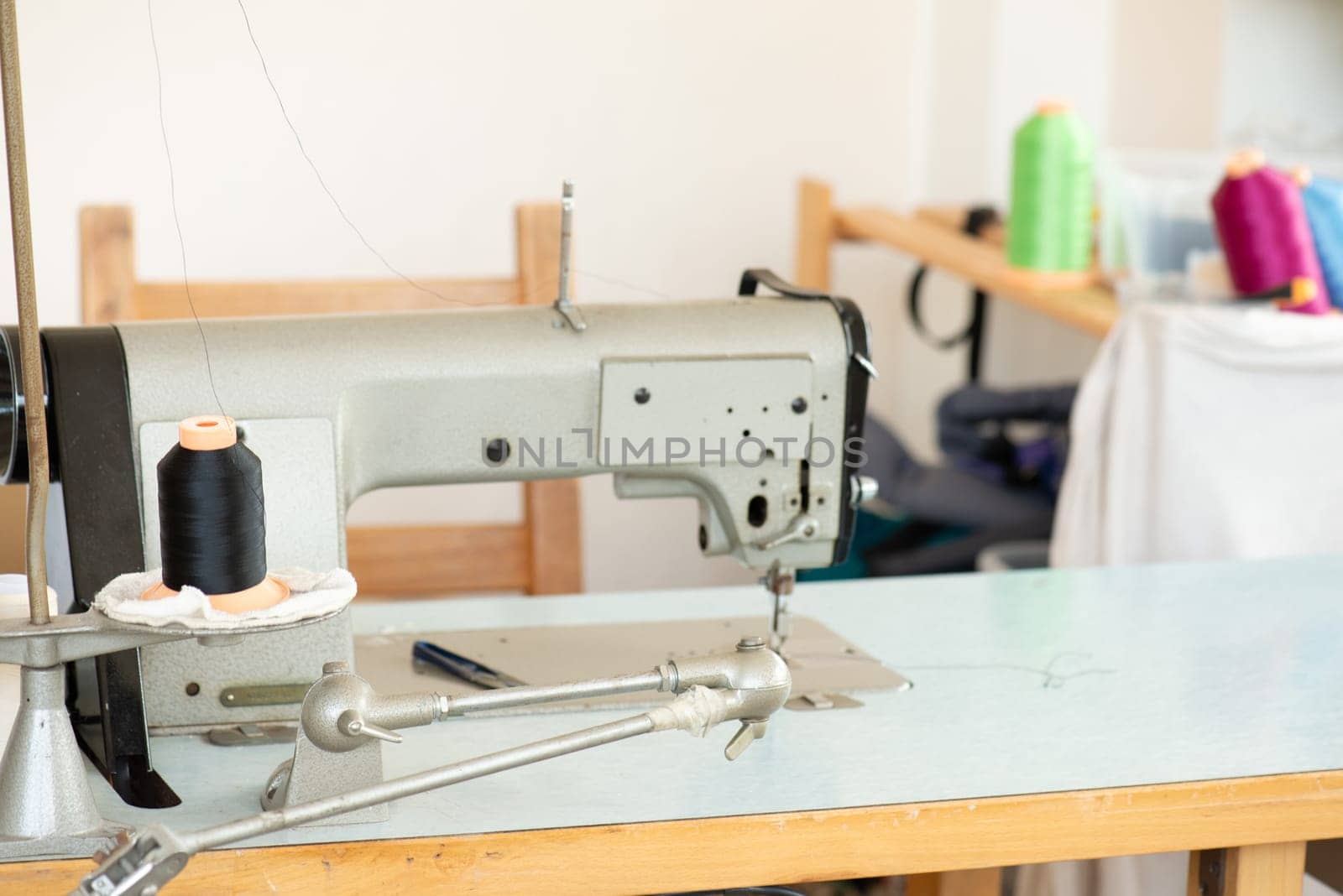 Industrial sewing machine with colorful thread, working place, manufacture for clothes, handmade, small local business