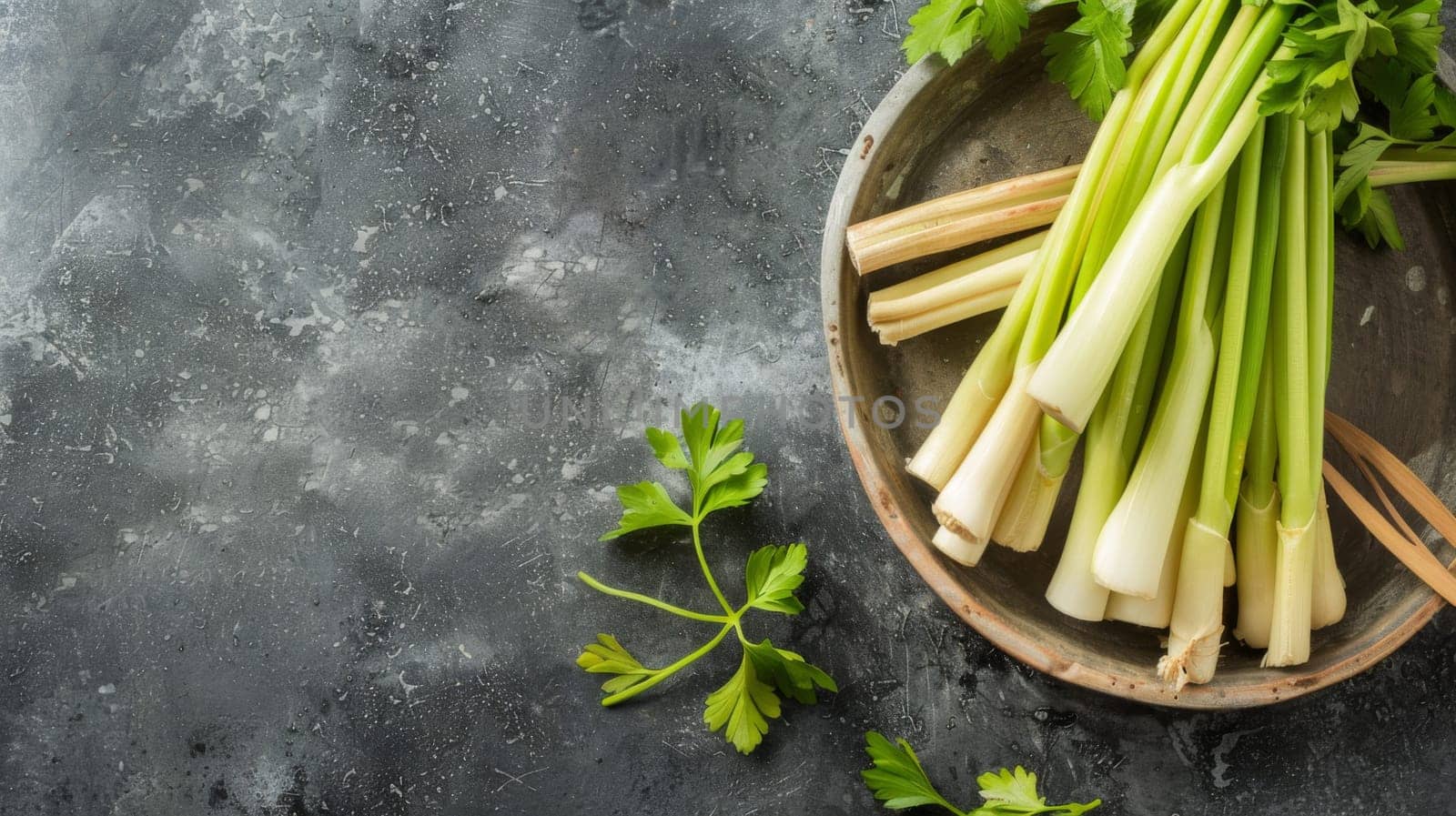 A white plate filled with fresh celery sticks sits on a wooden table. The celery is arranged neatly and is the main focal point of the image. The table is plain with no other objects in sight.