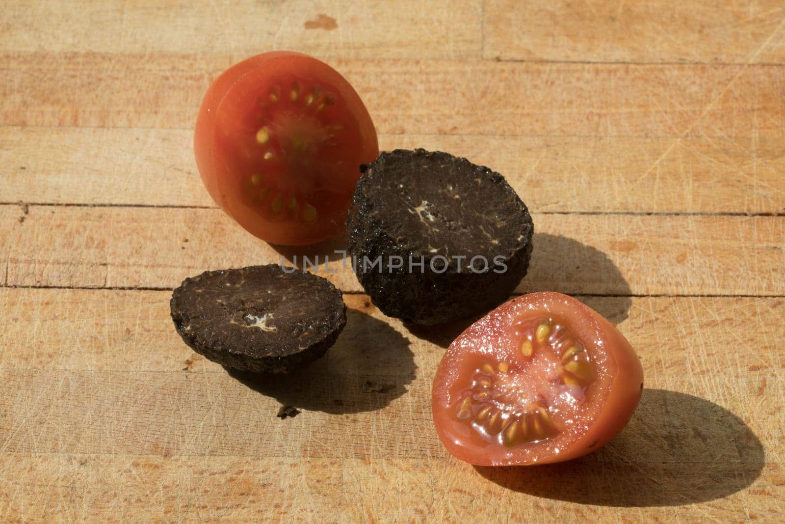 Tomato and black truffle isolated on a wooden cutting board