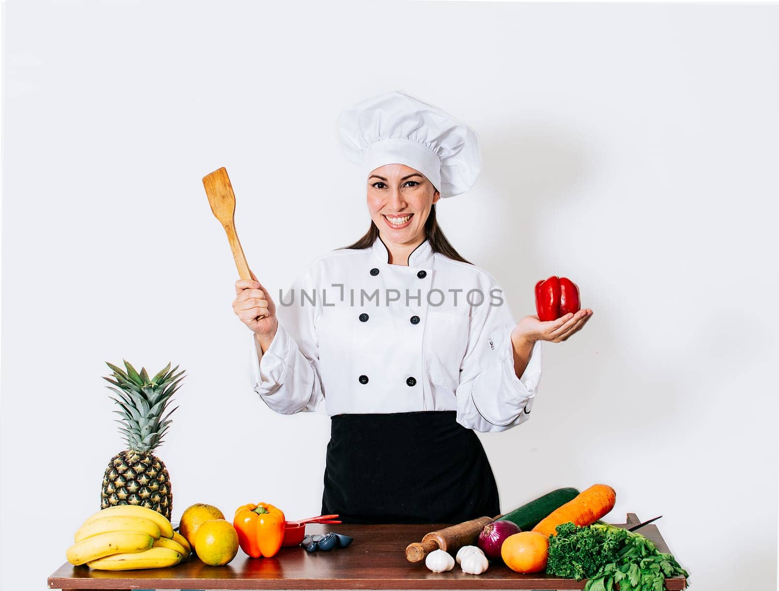 Woman chef holding a ladle on a table with vegetables, A smiling woman chef holding a ladle and vegetables, portrait of a woman chef holding a ladle on isolated background