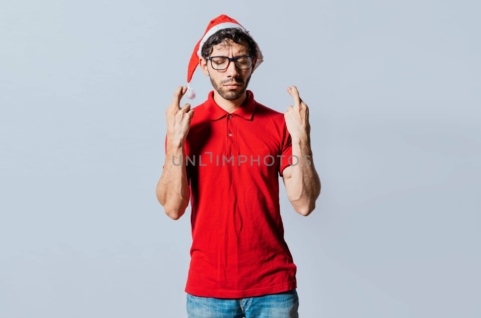 Handsome man in christmas hat making a wish on isolated background. Guy with christmas hat making a wish on isolated background, Hopeful man in christmas clothes making a wish
