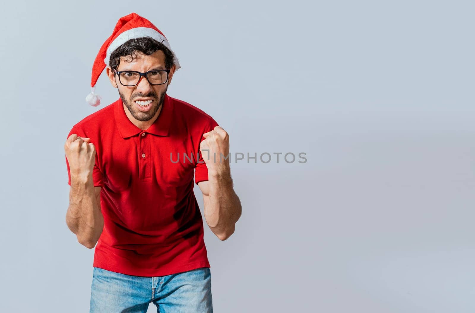 Man with beard and christmas hat angry looking at camera isolated. Furious christmas man looking at camera. People in christmas hats angry and furious looking at the camera.