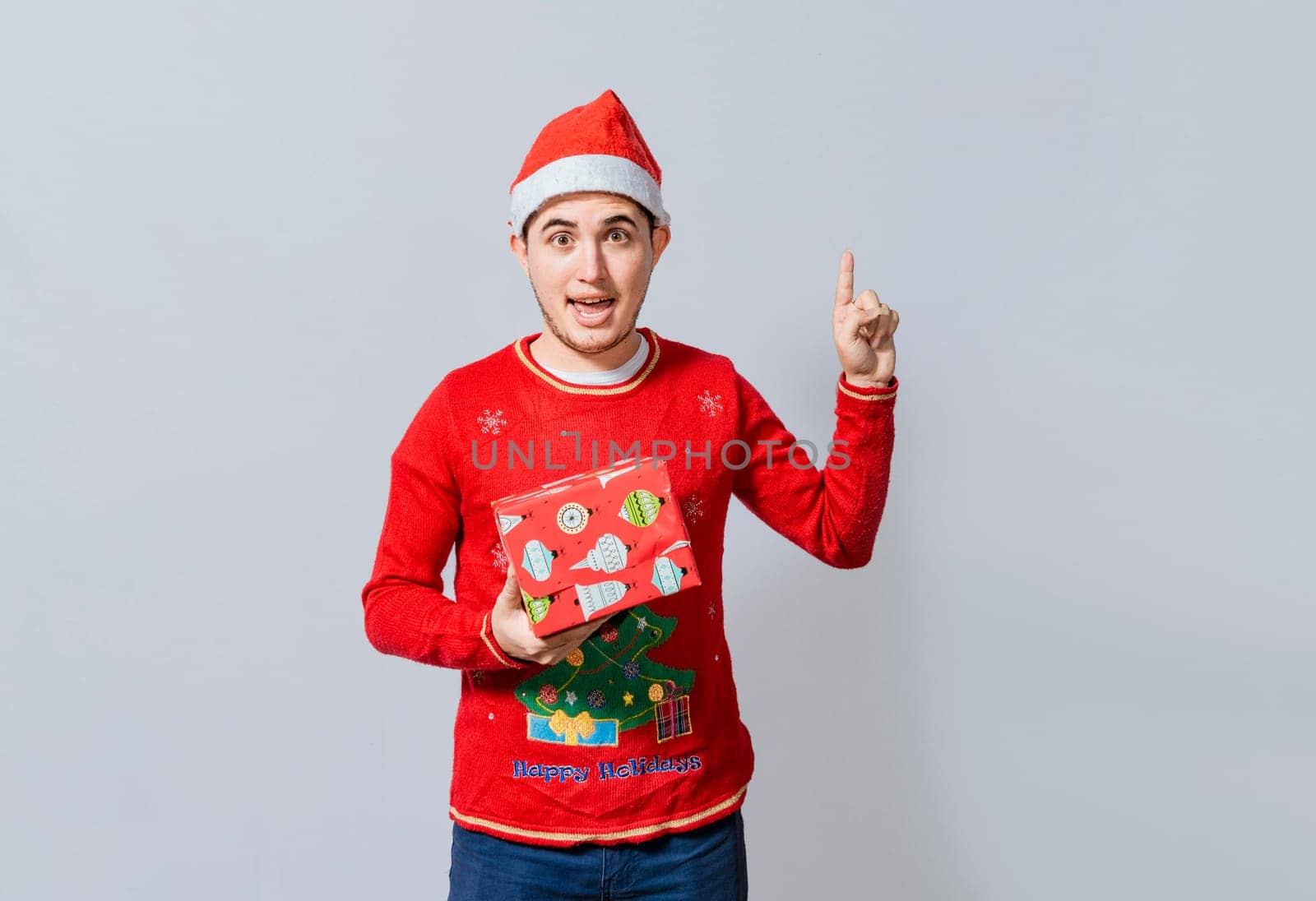 Amazed christmas man holding gifts pointing up. Surprised christmas man holding gifts and pointing up. Christmas man pointing a promo, Christmas man with surprised face holding a gift pointing up