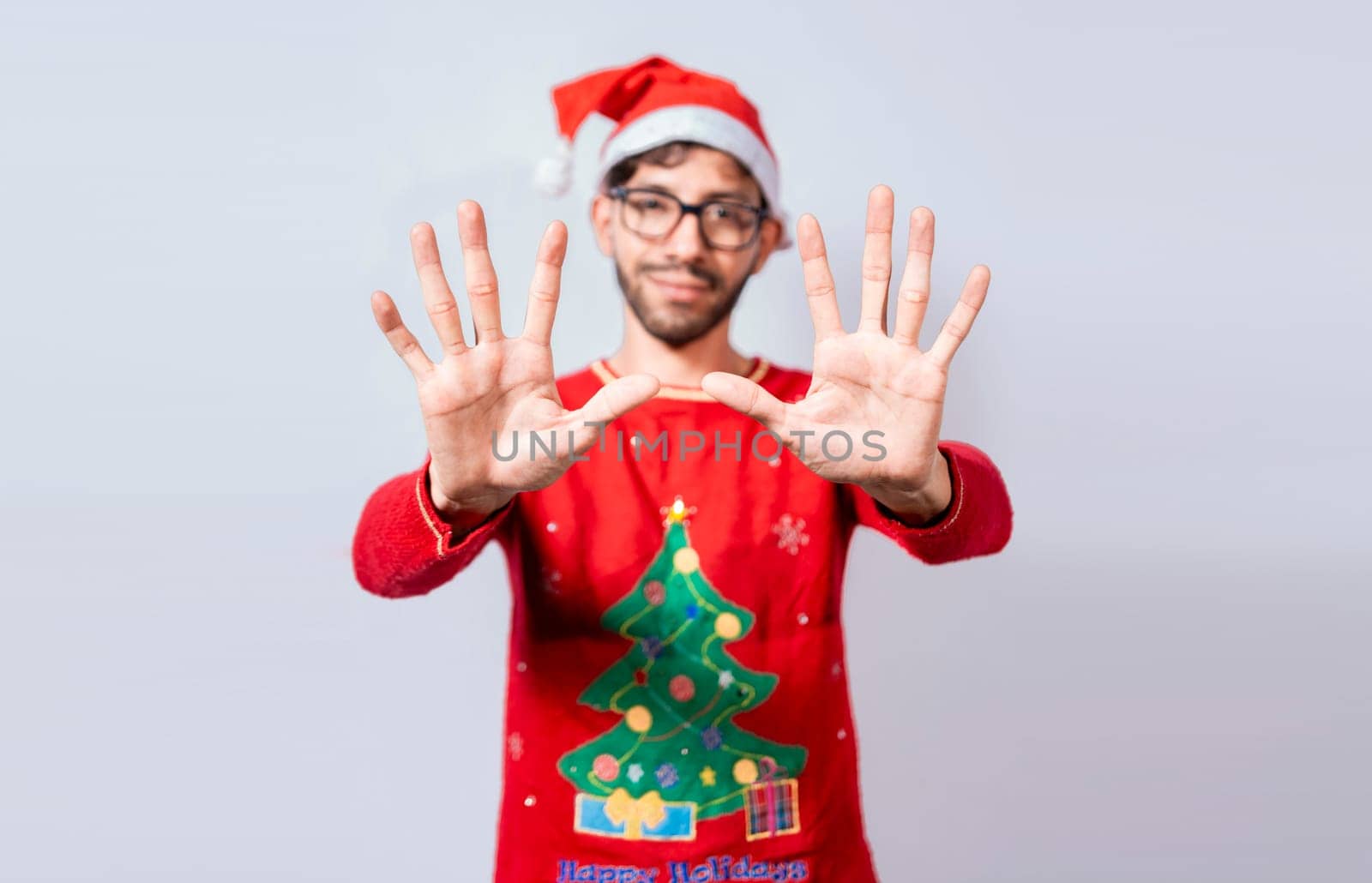 Man in christmas hat counting number ten with fingers. Christmas young man counting number ten with hands. Concept of man in christmas costume counting number ten isolated