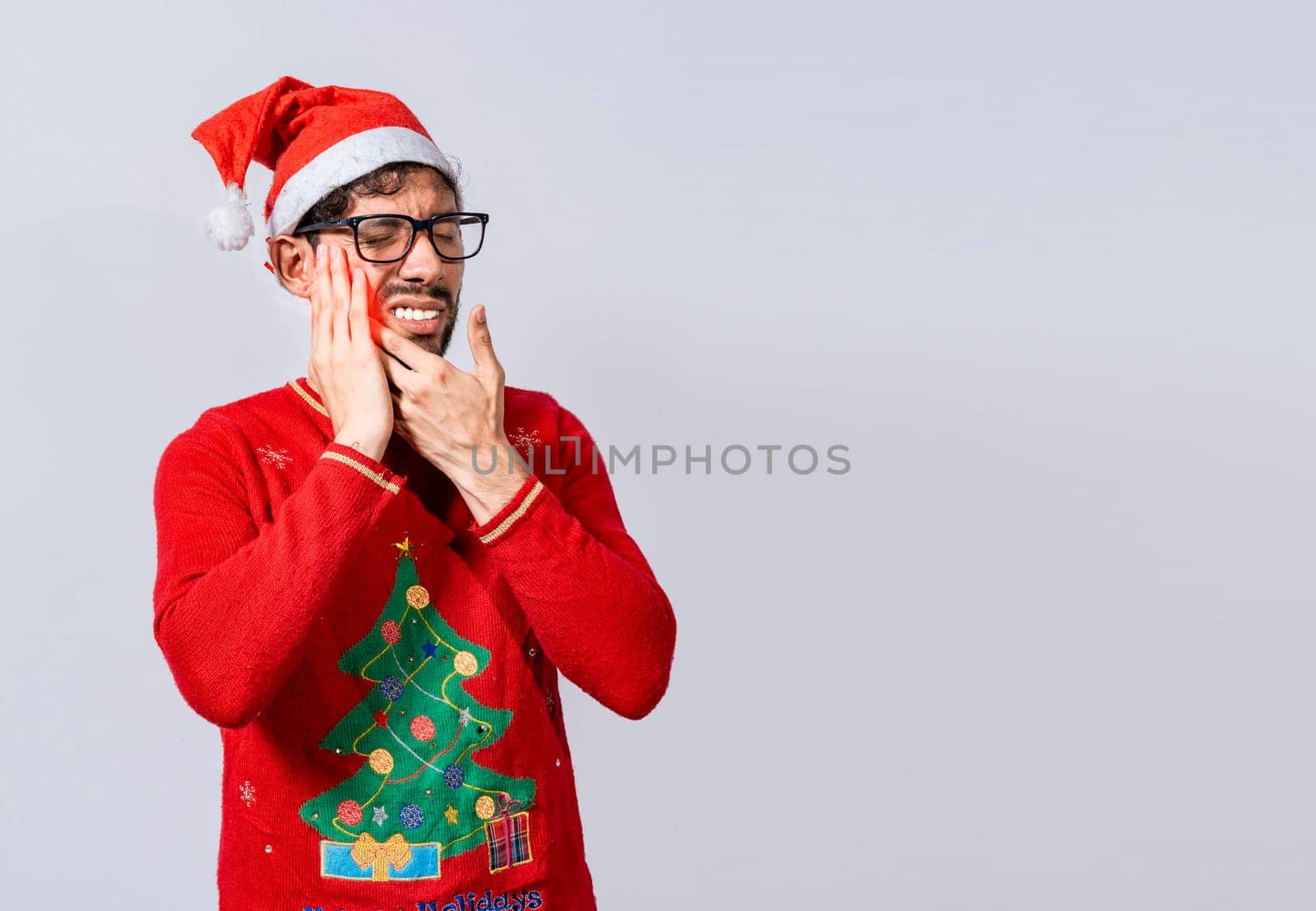 Man in christmas sweater with toothache, Young man in christmas hat with toothache isolated, Man in christmas hat in pain touching his tooth. Christmas toothache concept