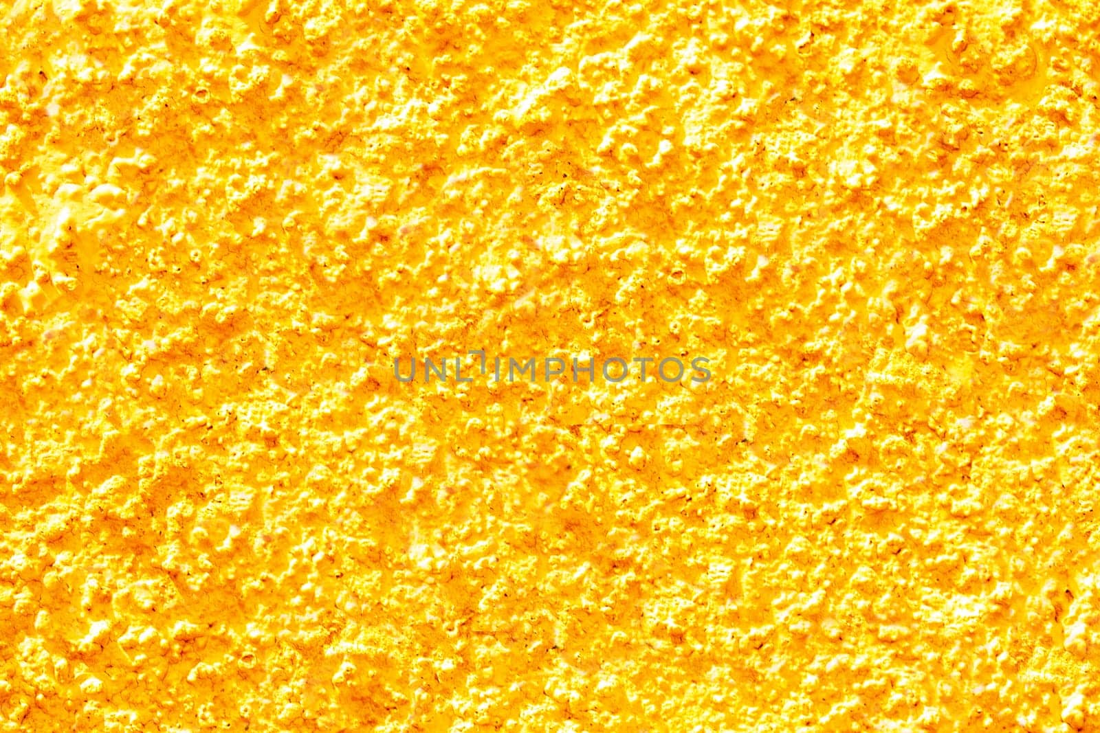 Gold yellow texture of a concrete wall. Closeup of yellow painted background of a concrete wall with a hilly uneven surface. Abstract backdrop.