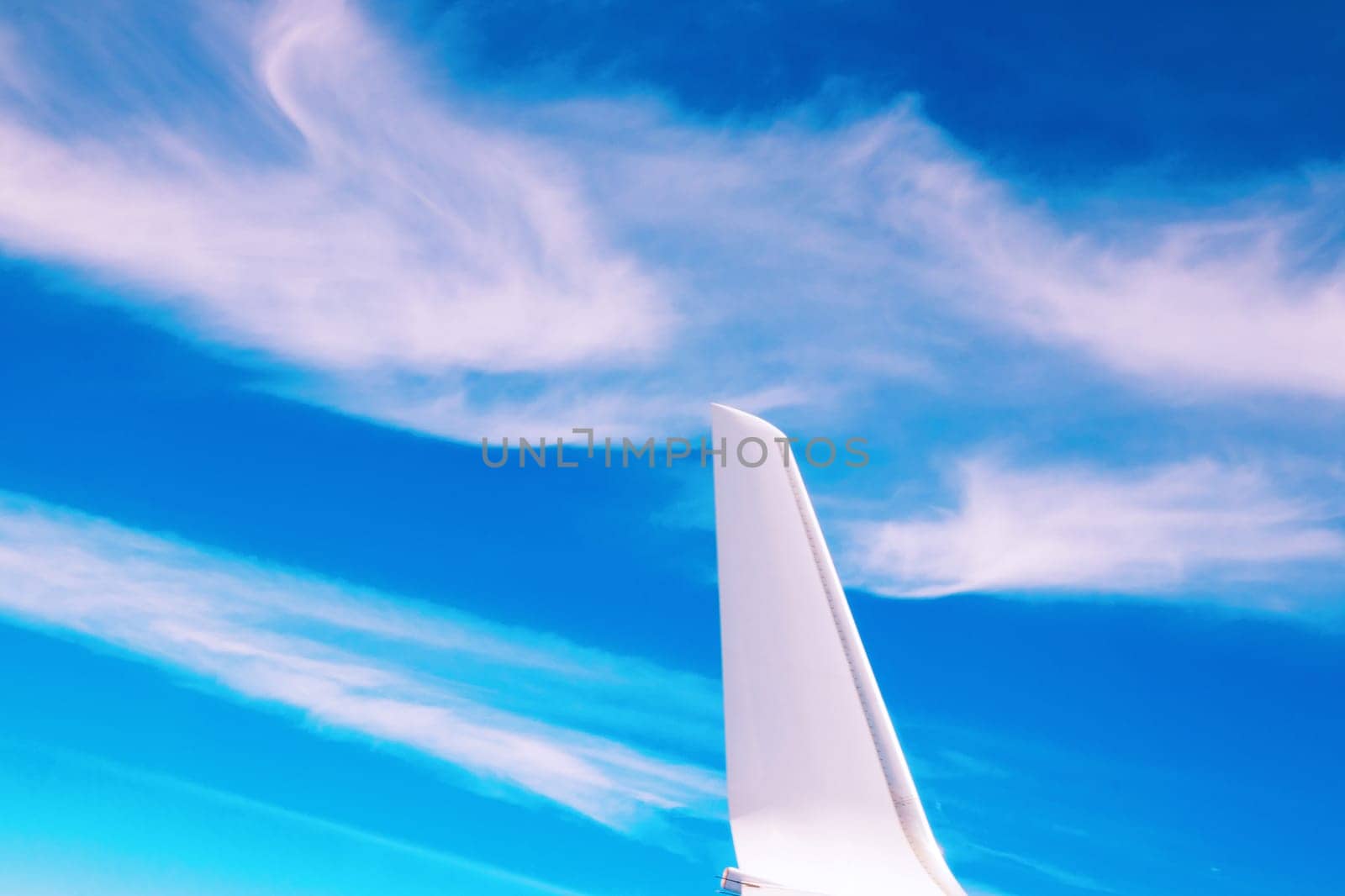 View of the part of a wing of an aeroplane or airliner in flight out of the window with blue sky and light clouds. Wing of aircraft. Copy space.