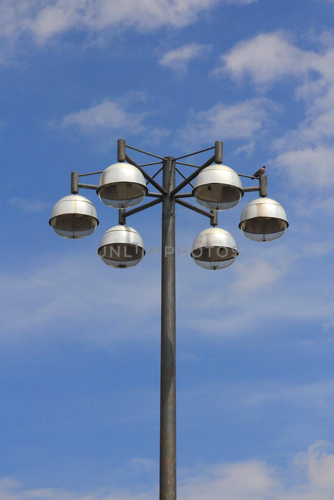 Street light with six lamps, and blue sky in the background