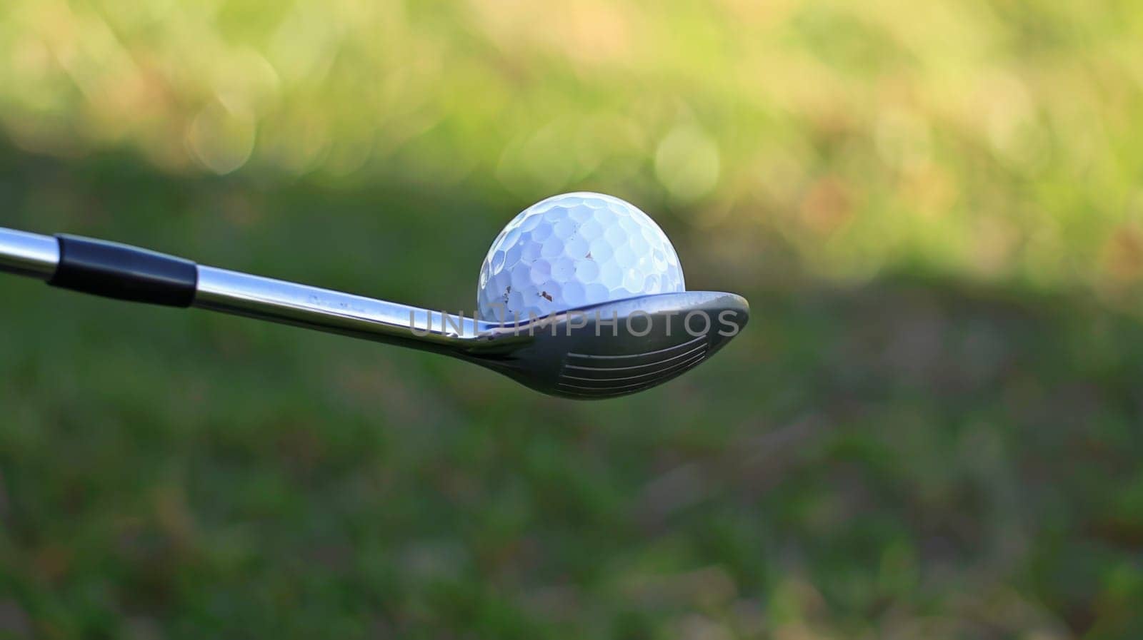 A detailed view capturing a golf club and a golf ball in close proximity, ready for a swing on the golf course. The dimpled texture of the ball contrasts with the sleek surface of the club, highlighting the anticipation of a precise shot.