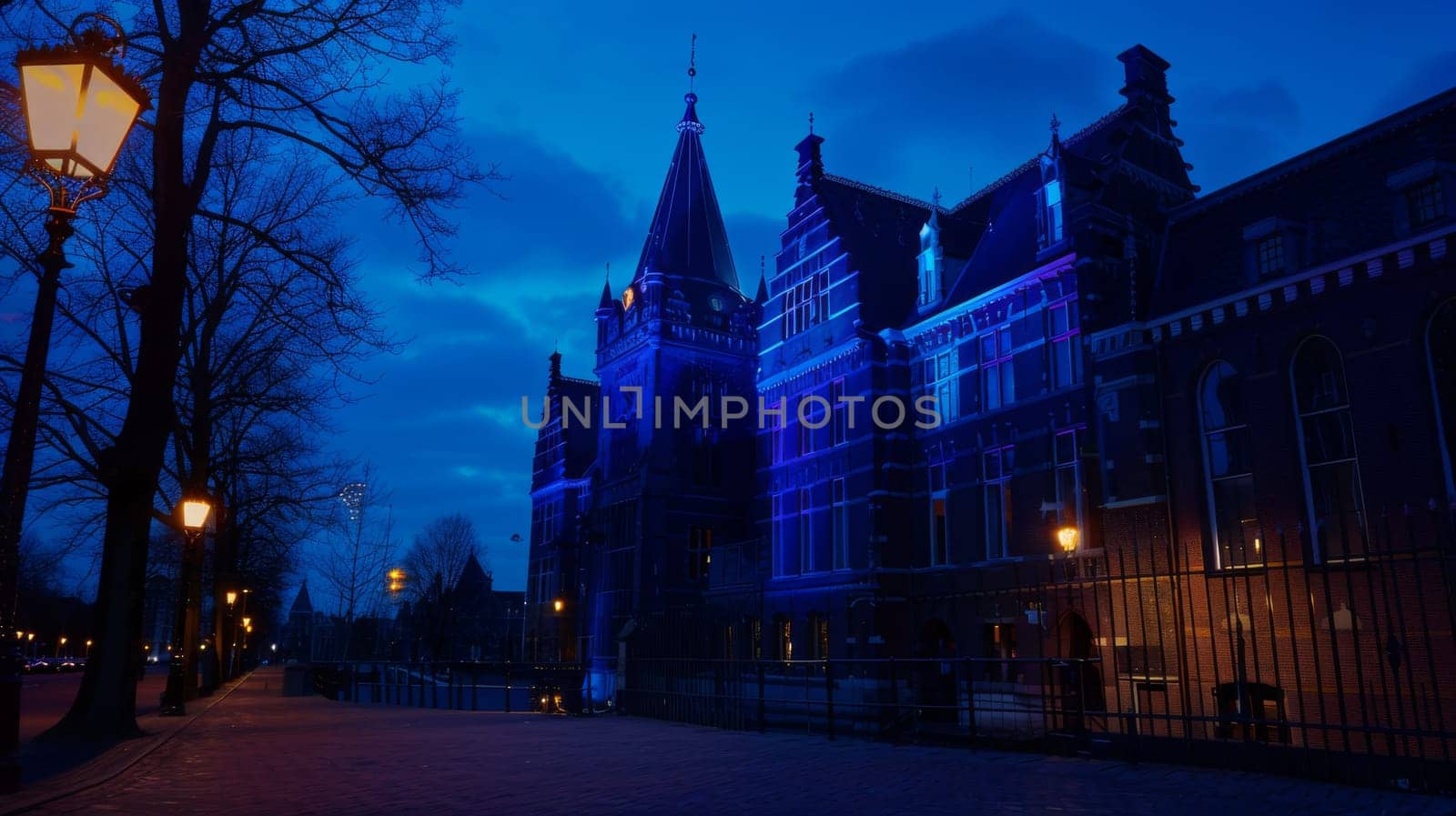 A building with a clock tower illuminated at night, casting a warm glow in the darkness. The clock face stands out, displaying the time against the dark sky.