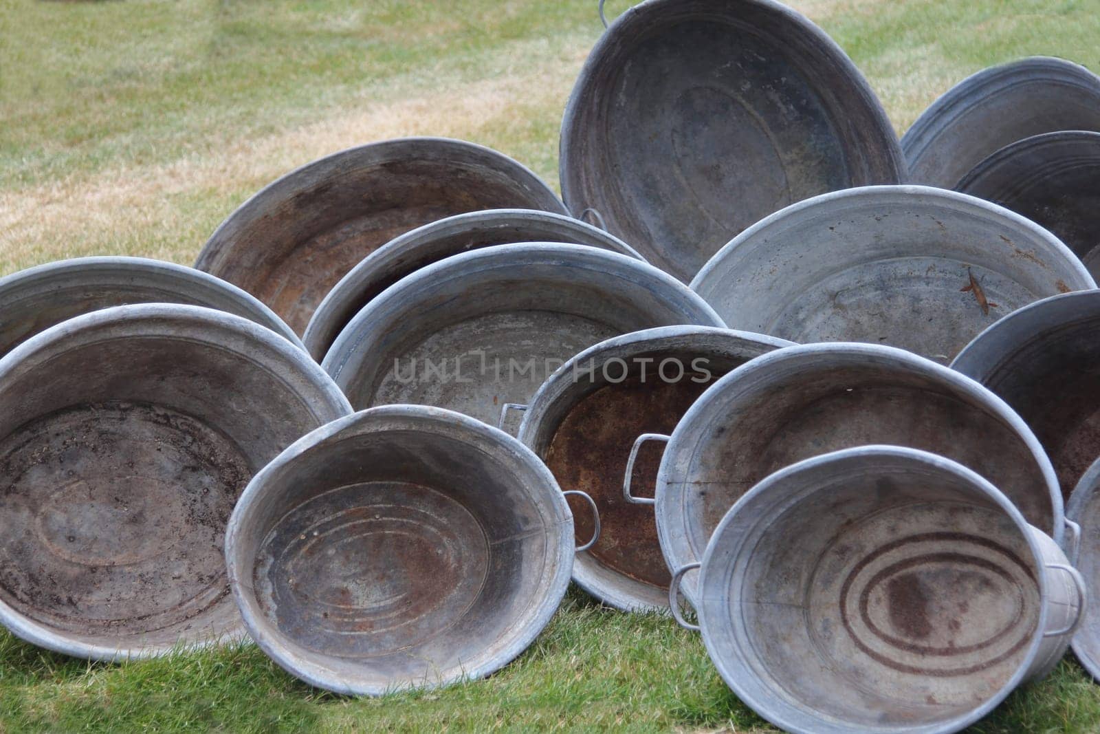 several antique zinc tubs placed on a green meadow