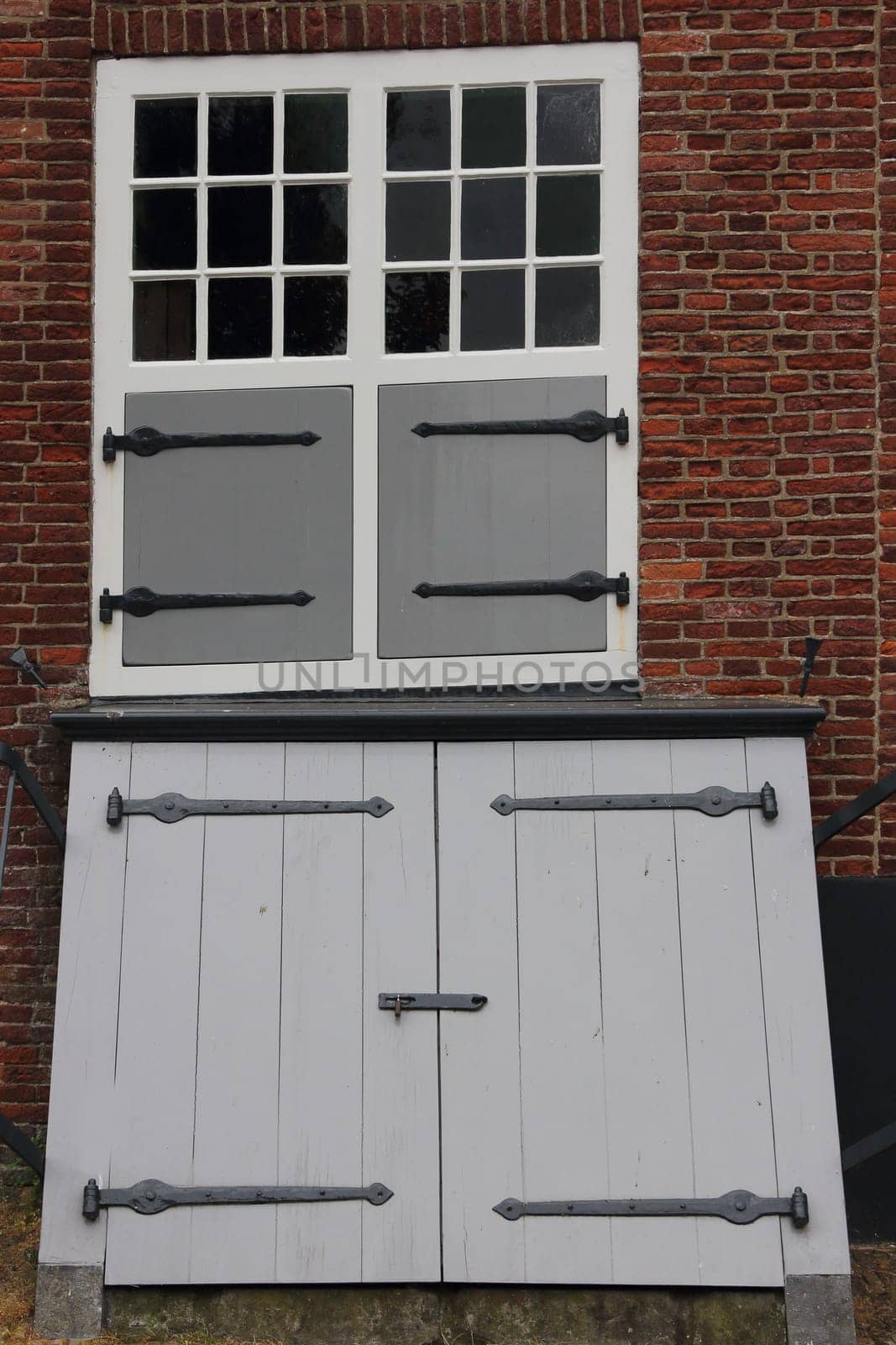 Two white windows with sprouts, in a brick wall