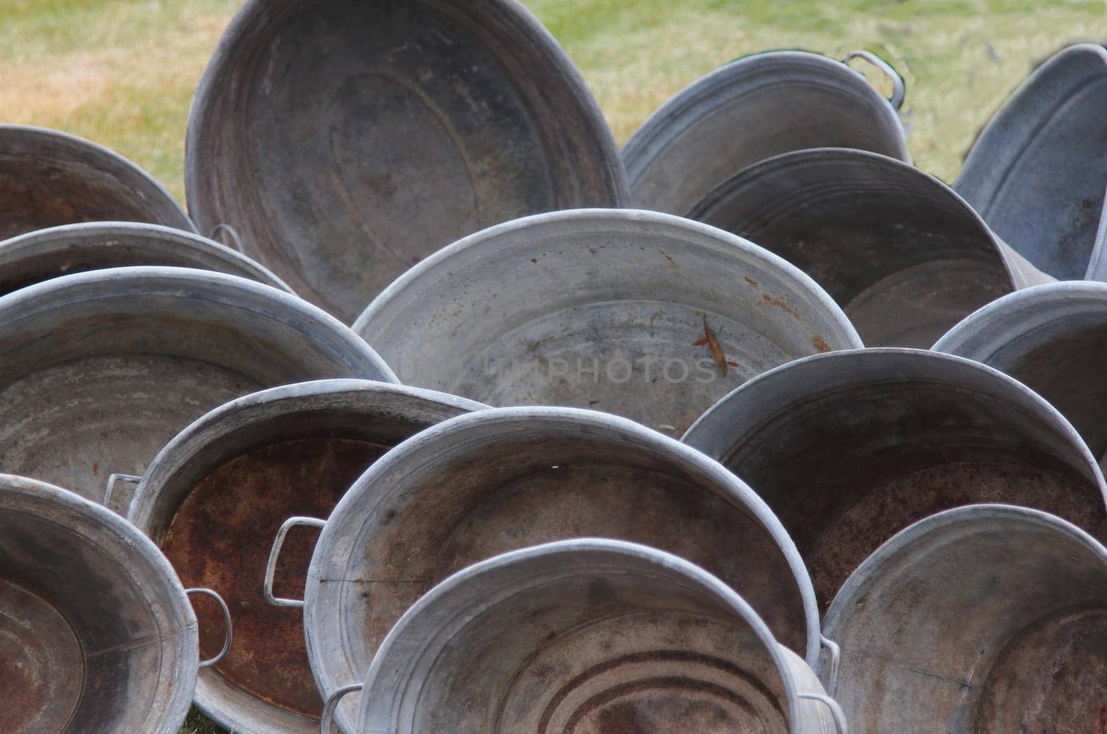 several antique zinc tubs placed on a green meadow
