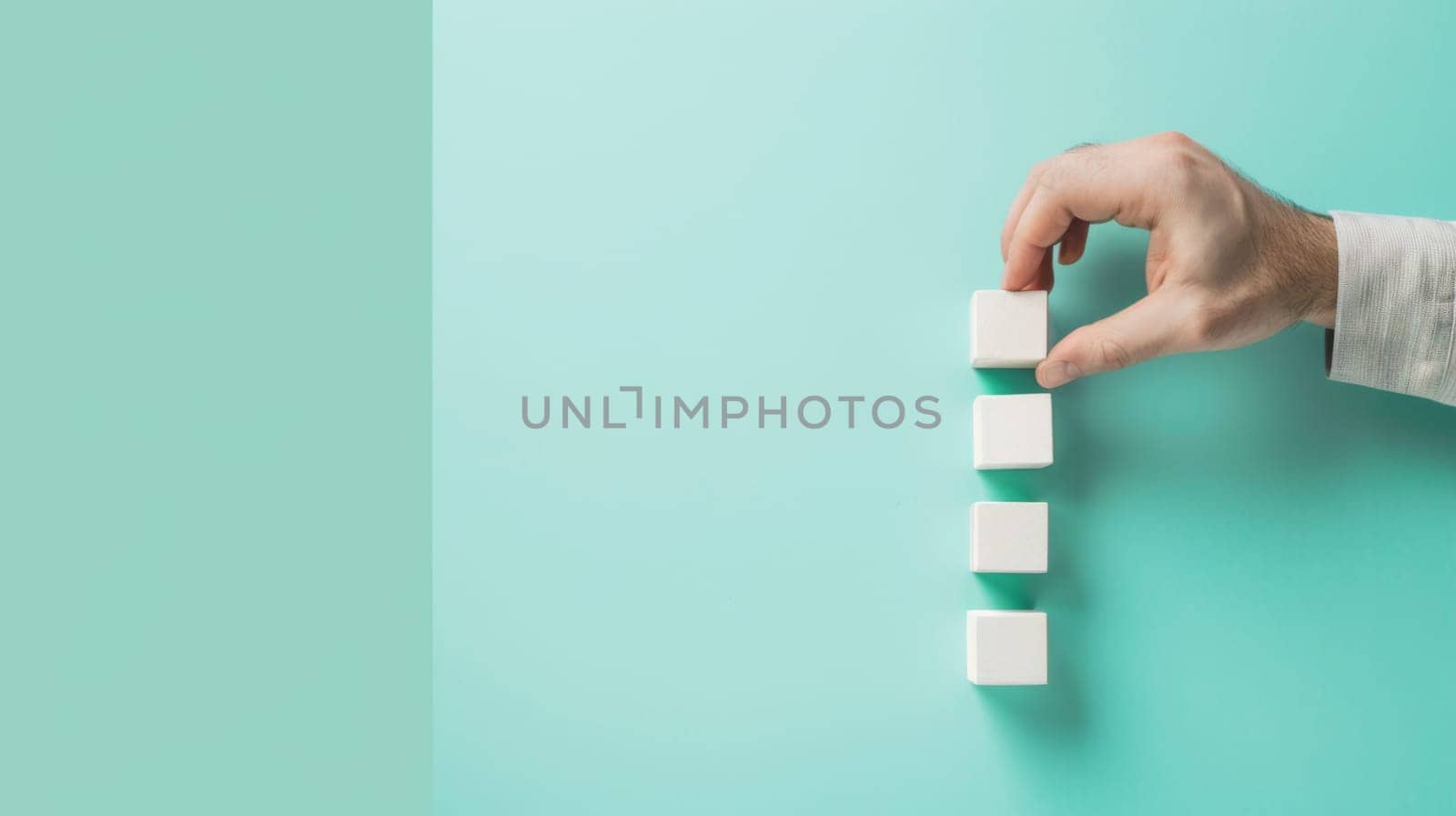 A person is seen holding a white foam block in front of a vivid green wall. The individuals hand grips the block firmly, showcasing it against the background color.