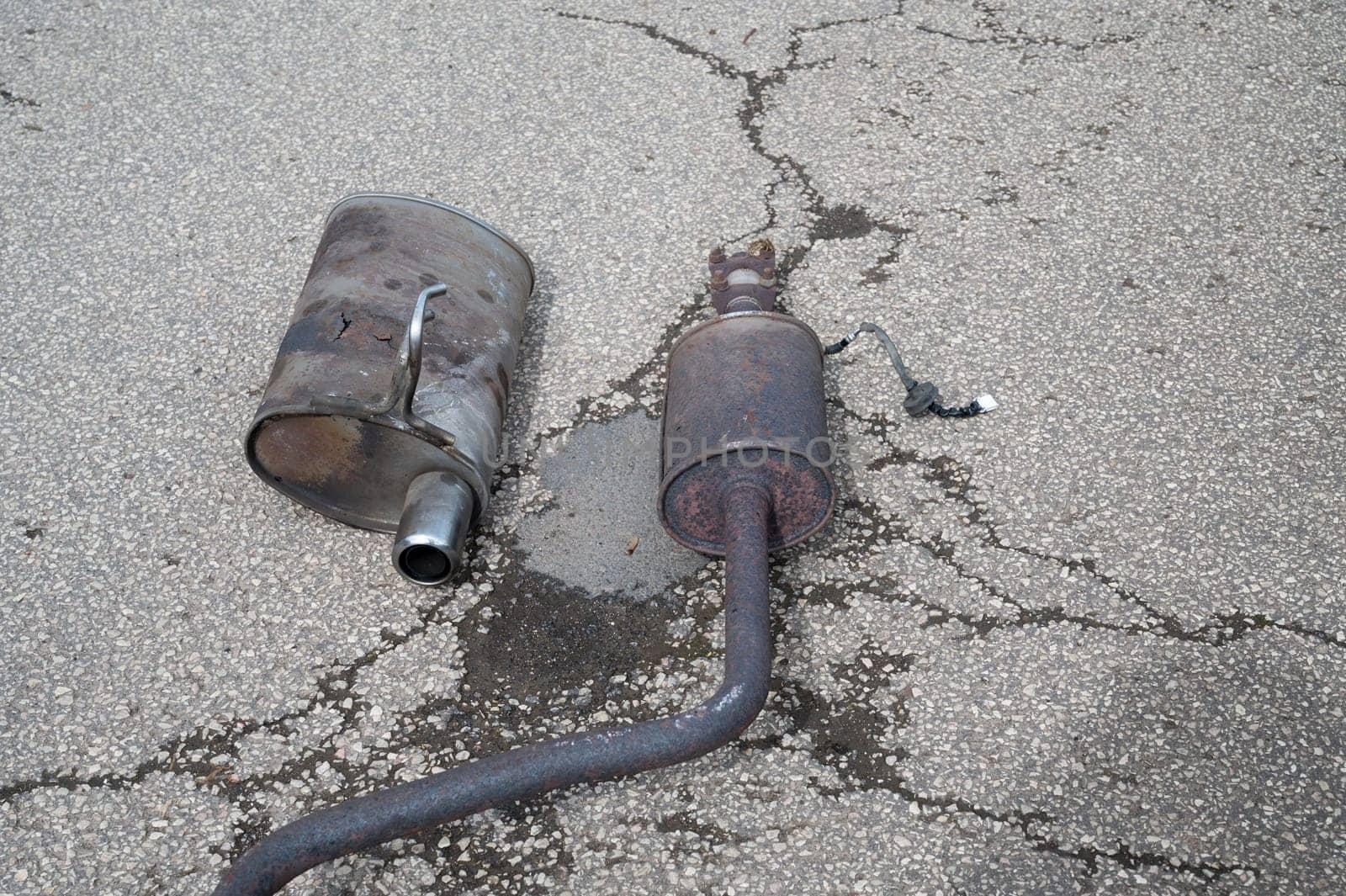 Broken exhaust and muffler of a car, rusted silencer fallen down on the road, breakdown of vehicle
