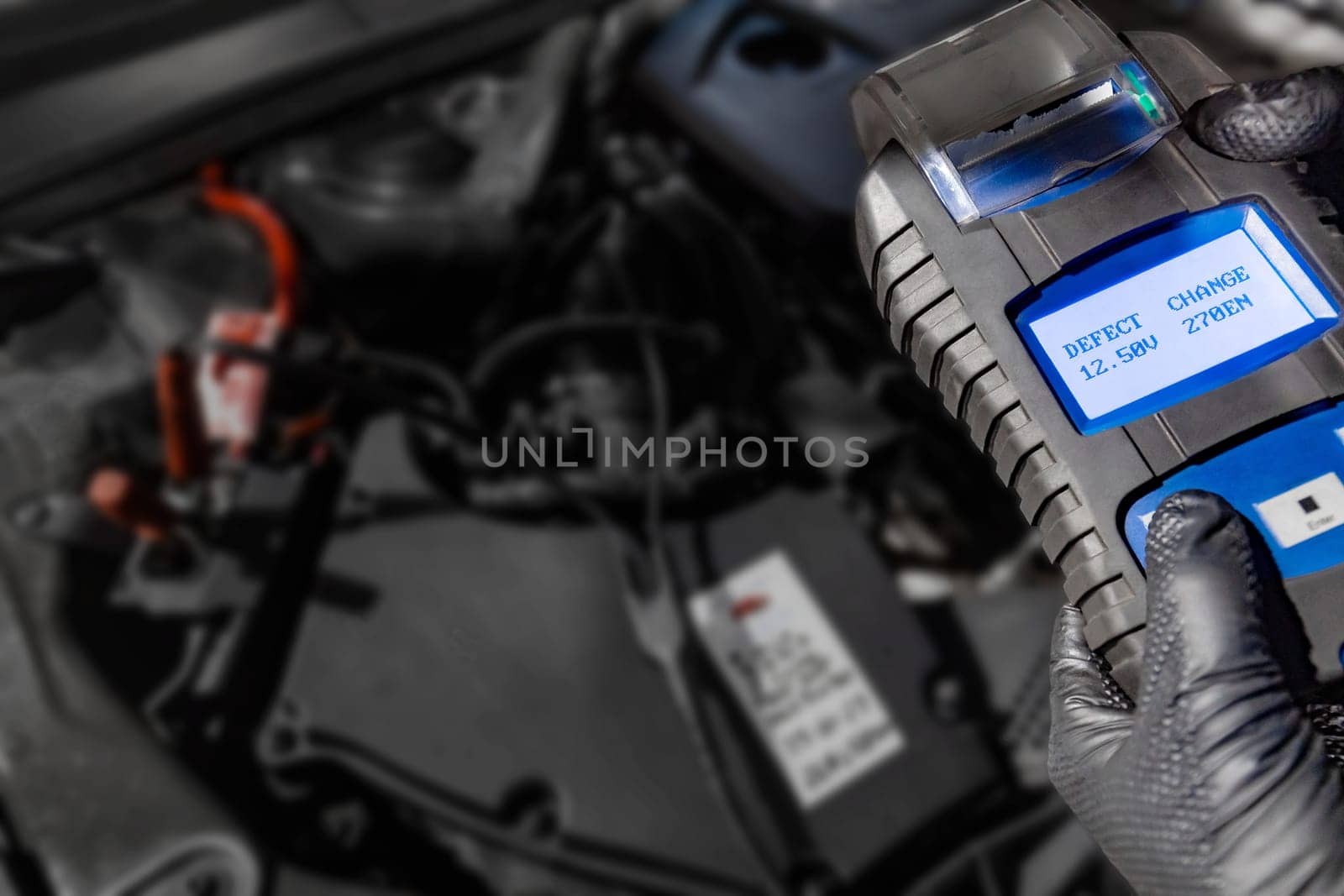 Explore automotive diagnostics as a mechanic holds a battery tester under the hood, displaying Defect and Change on the screen above the car battery, indicating the need for replacement. Ensure optimal vehicle performance with timely battery maintenance.