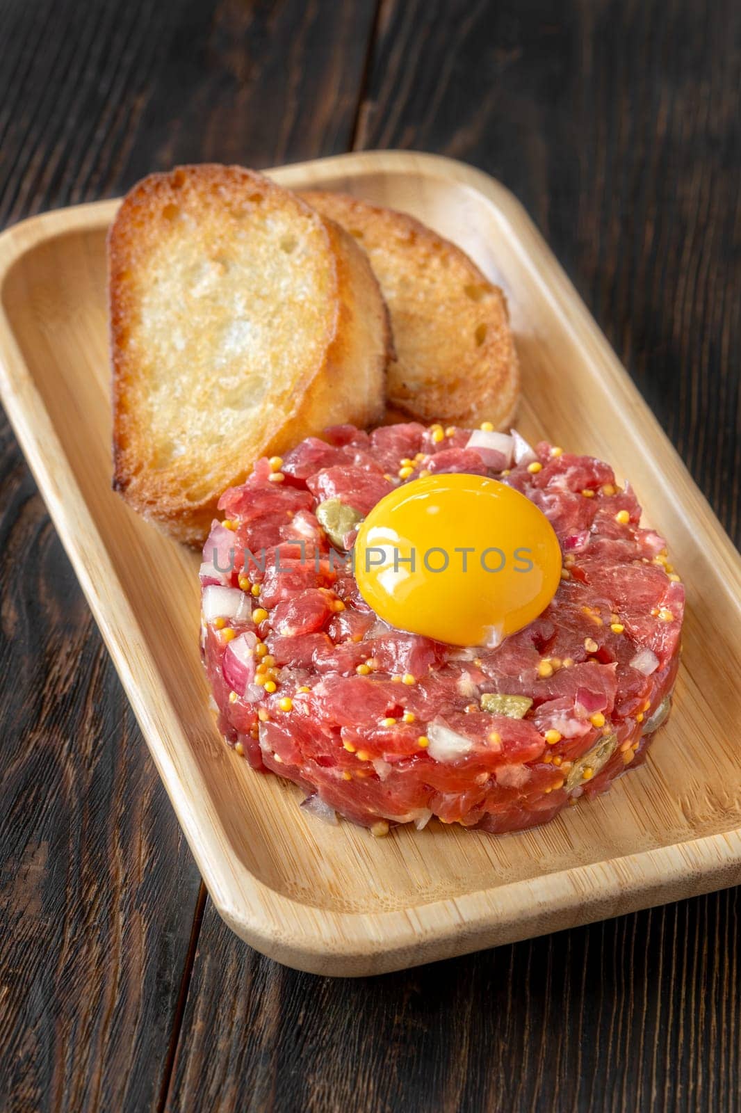 Portion of Beef steak tartare topped with a raw egg yolk