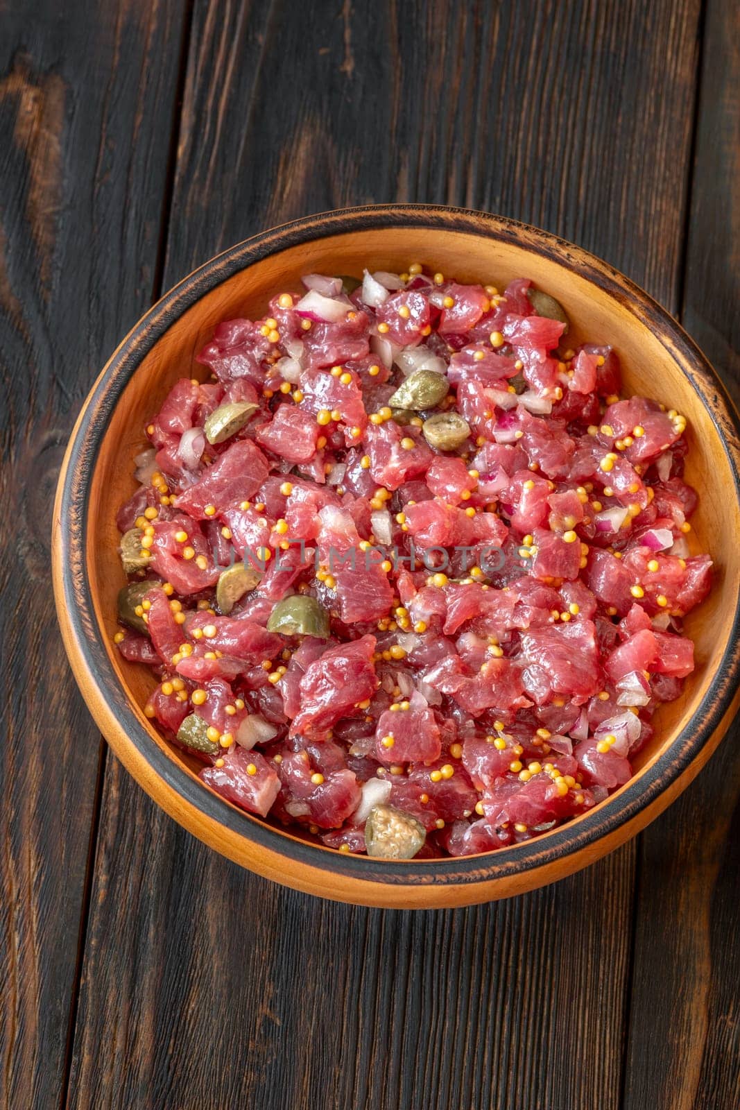 Portion of Beef steak tartare in wooden plate