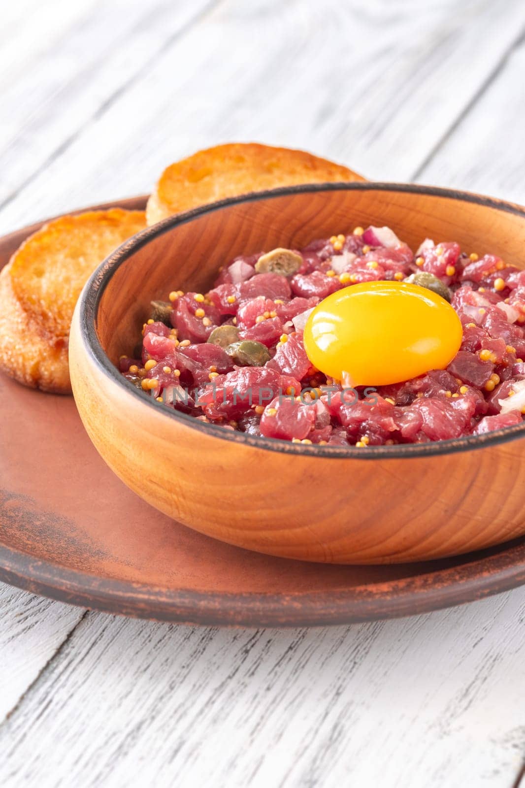 Portion of Beef steak tartare topped with a raw egg yolk