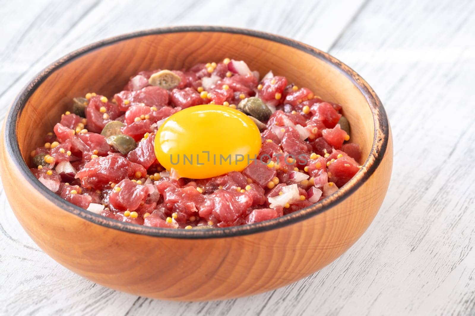 Portion of Beef steak tartare topped with a raw egg yolk
