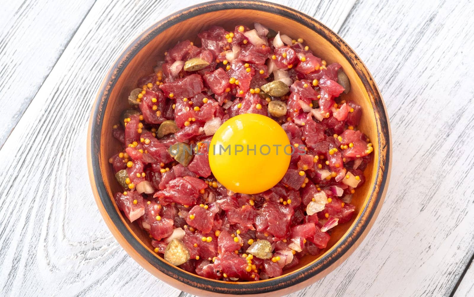 Portion of Beef steak tartare topped with a raw egg yolk