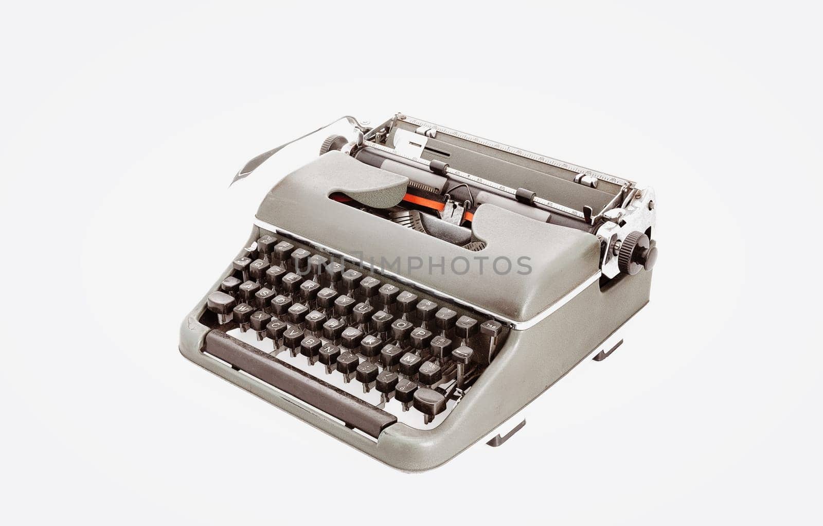 Metal typewriter reminiscent of bygone days with dark keys and an iconic lever. Photographed from above at a three-quarters angle, starkly offset by white