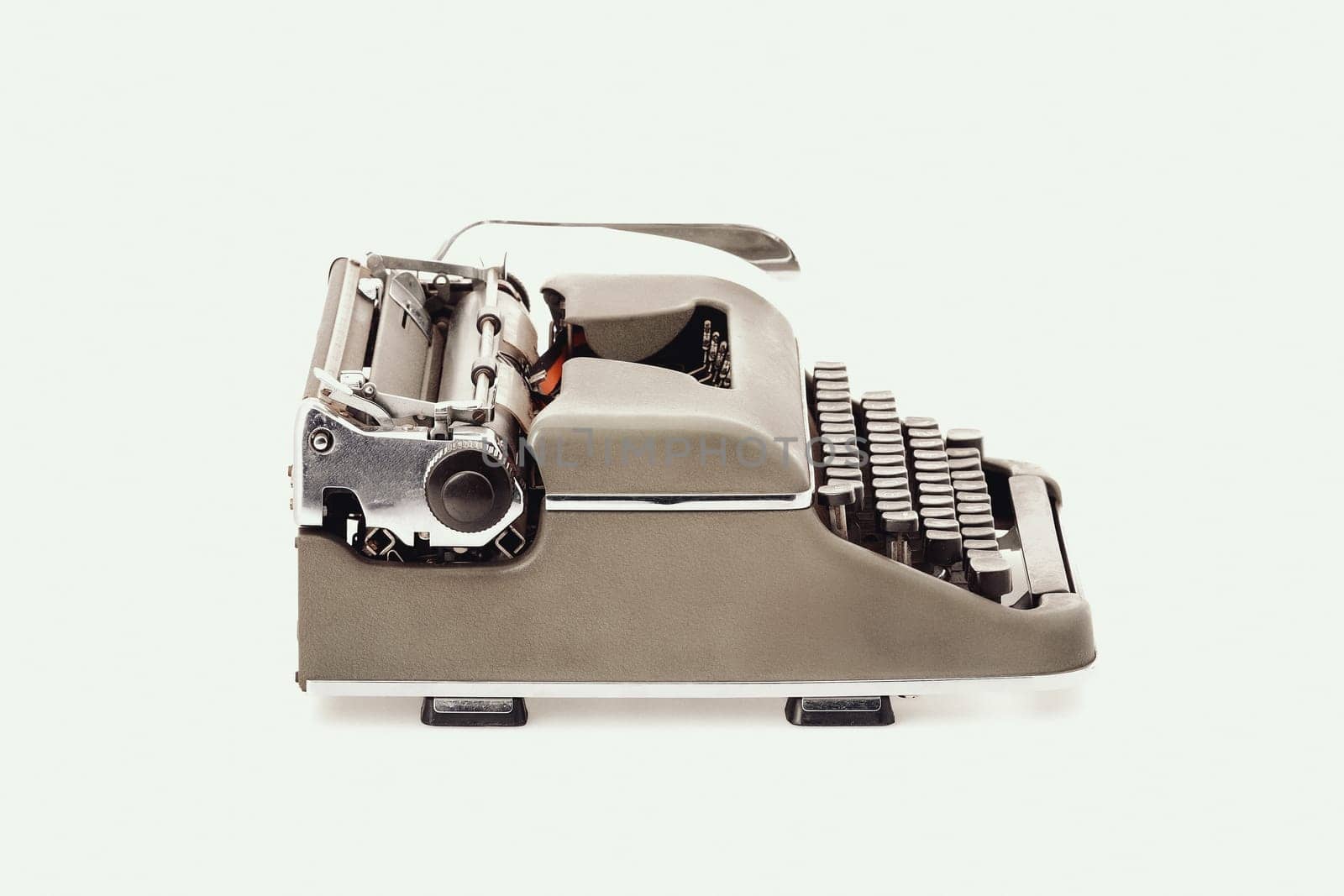 Vintage metal typewriter with black keys and a prominent return lever. Side view, slightly from above, against a white background