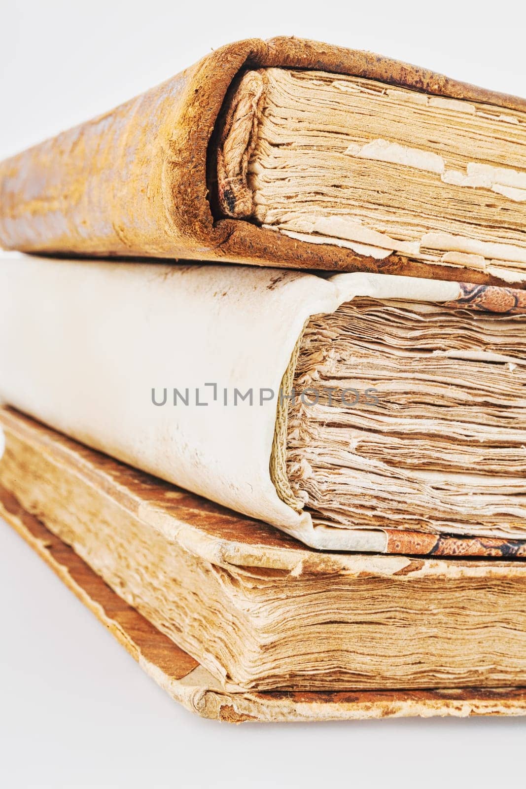 Centuries-old books, layered atop one another, all showcasing beautifully distressed leather exteriors. They hold tales of adventures and knowledge. Reading was once a privilege. Set against a white b