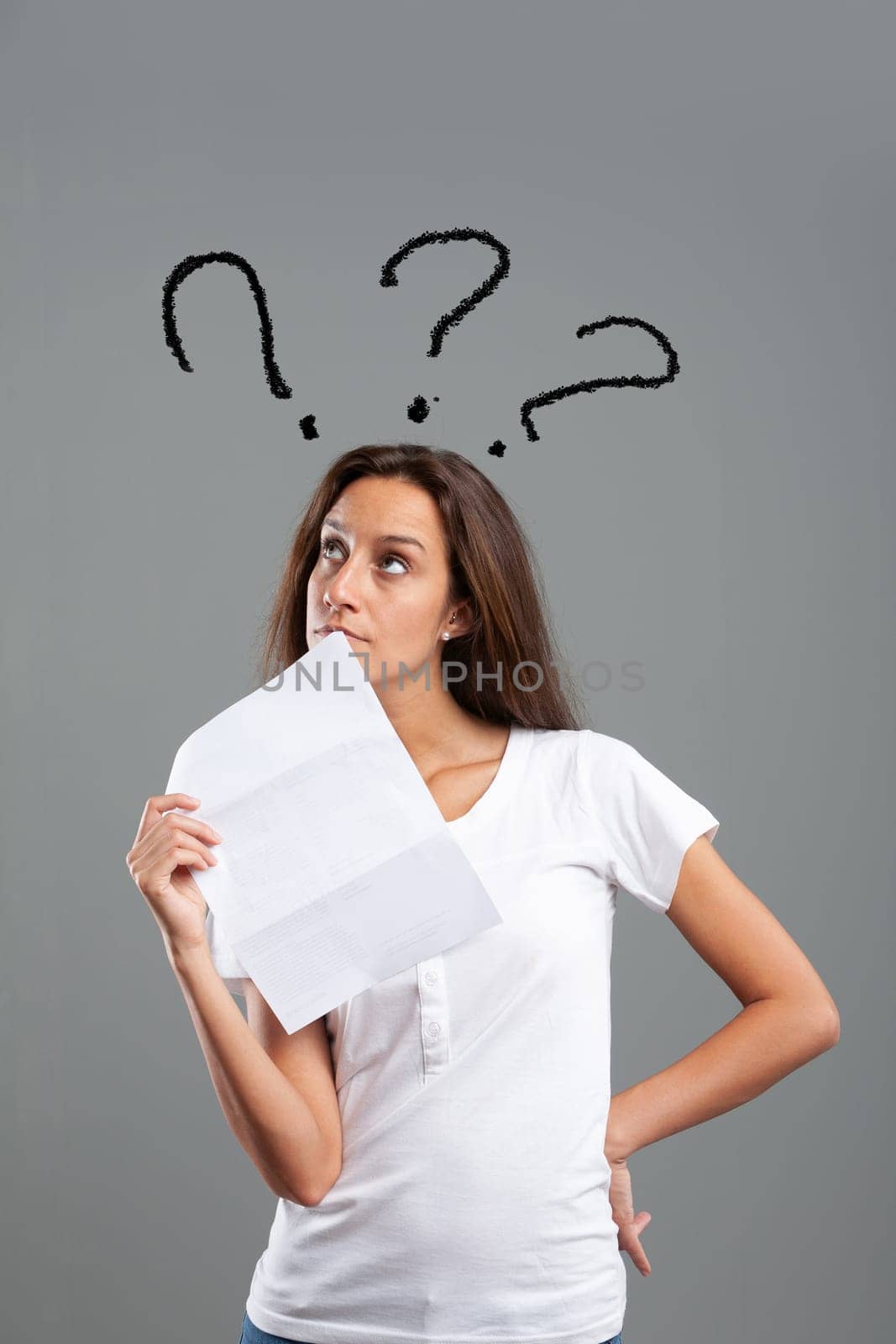 Thin young woman with letter causing her doubts or thoughts, carries a hand at her side and the document in front of her face, the graphic represents three question marks