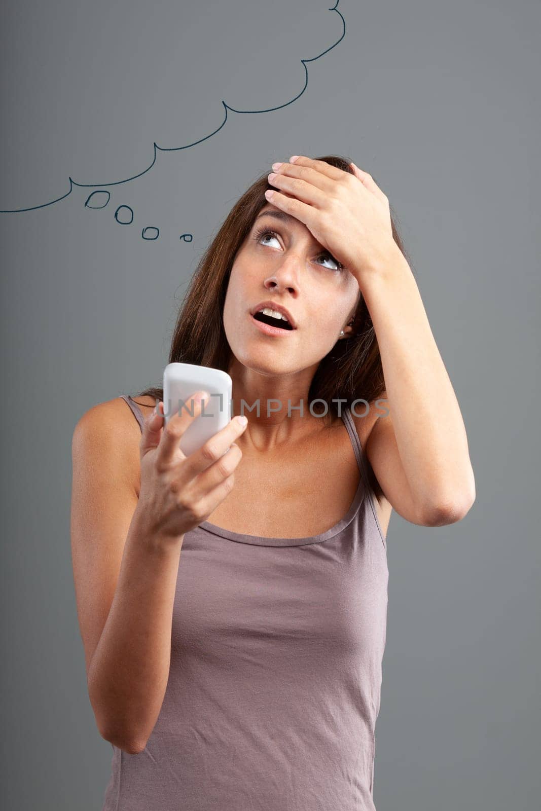 Emphatic and expressive portrait of a slender young woman with a smartphone in her hand looking up to the left as if a great idea or a memory had suddenly occurred to her, such that she was surprised
