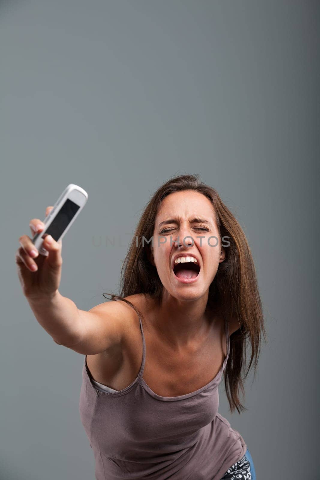 Athletically hurling her cellphone, the woman unleashes her anger-fueled violent strength, accompanied by a furious scream. She's completely fed up!