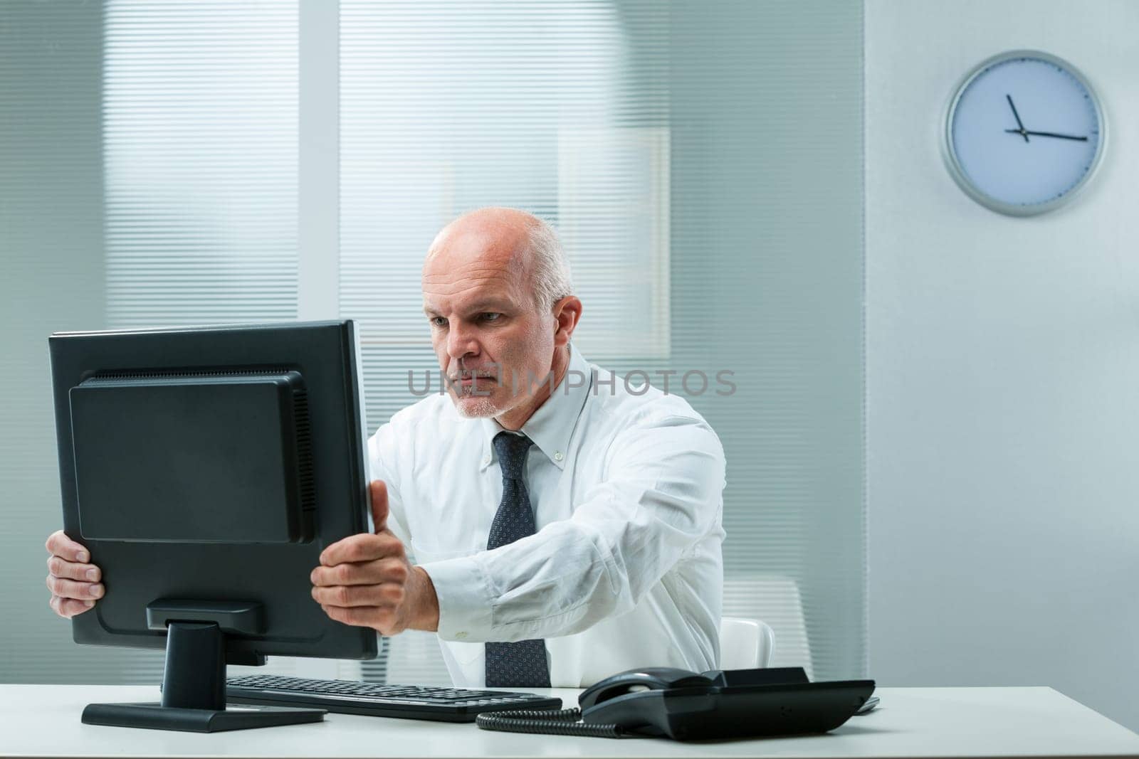 stern senior executive grabs his computer screen, hinting at financial problems or unforeseen mistakes. He seeks to swiftly rectify with his signature resolve
