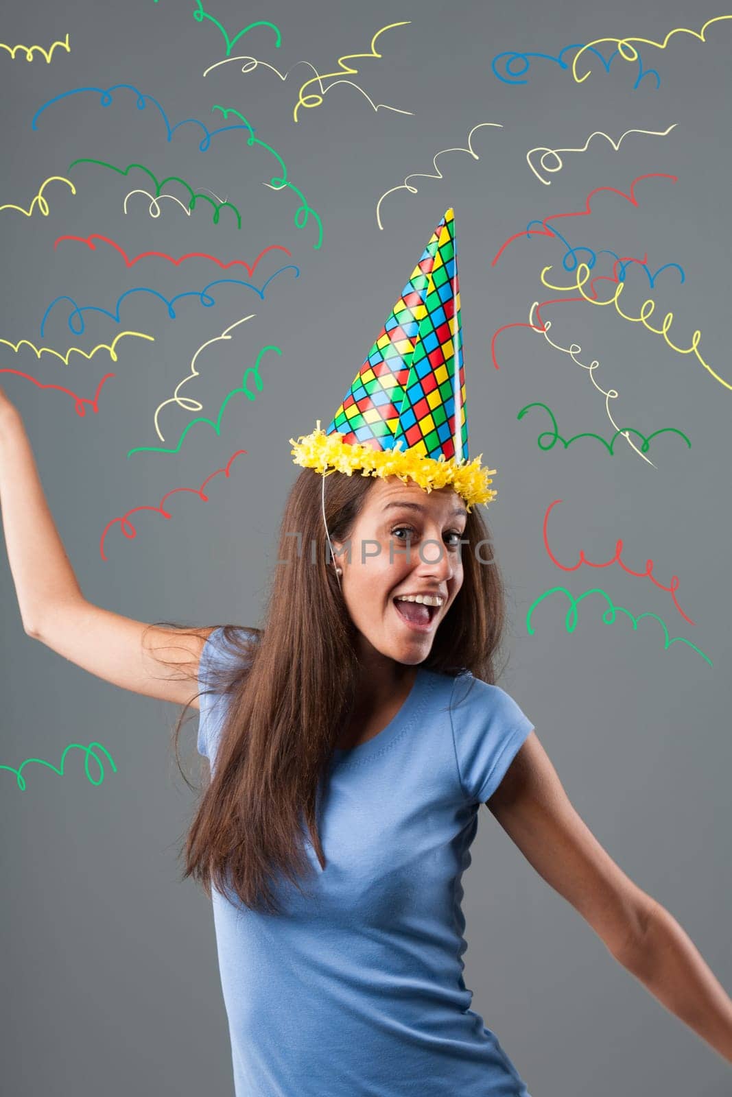 Girl in pointed hat, harlequin colors, and party horn enjoys amidst an explosion of colors and graphic confetti. Festivities, fun, anniversaries, and birthday celebrations