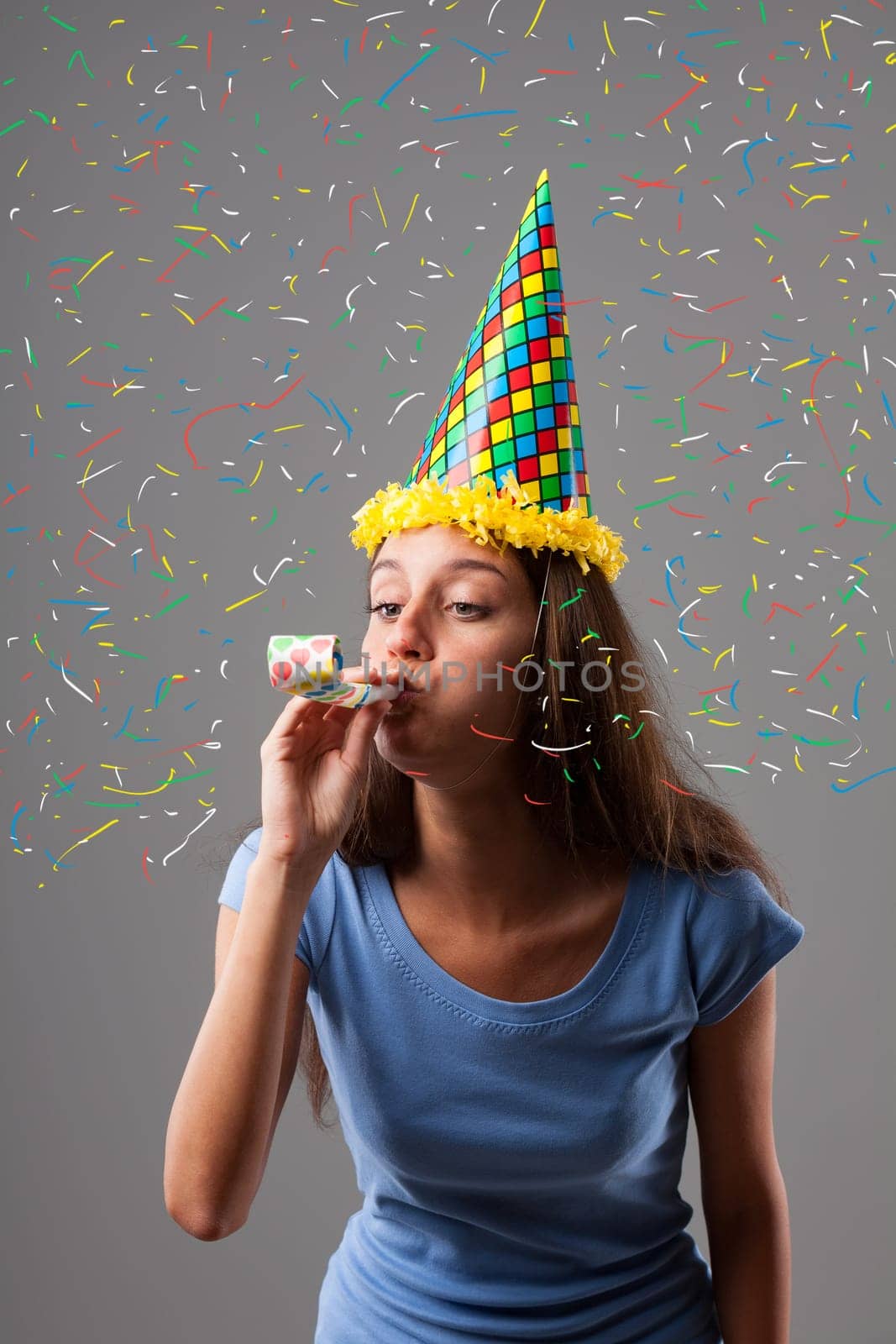 Party girl dons pointed hat, harlequin colors, and horn amidst colorful explosion of graphic confetti. Fun, festivities for anniversaries and birthdays
