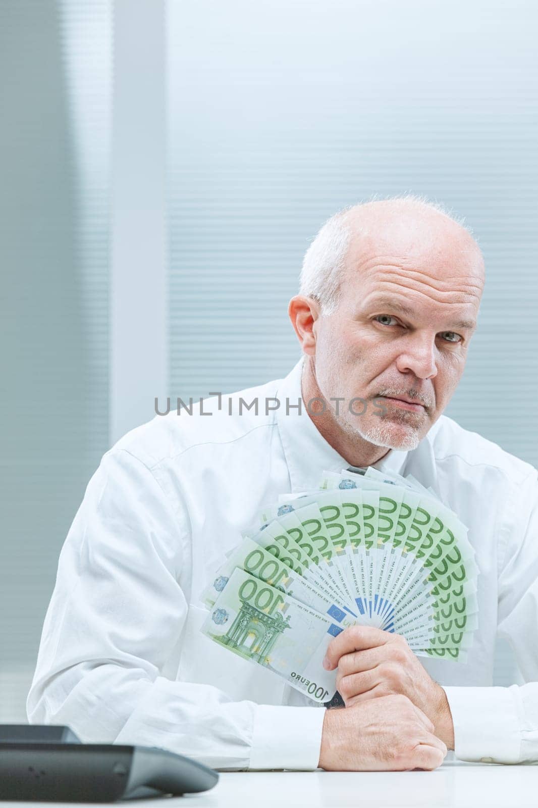 mature businessman in white shirt flaunts a fan of big European bills. Is it bribery, a small kickback, or mere ambition? Inefficient bureaucracy often paves the way for graft