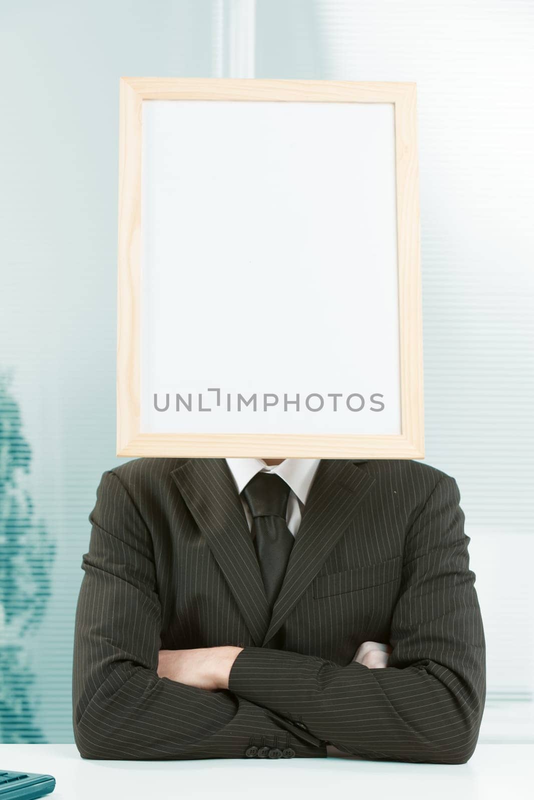 Cartel head. White collar with a white sign for your COPYSPACE instead of a head. Sitting at desk in formal dress with arms folded, conveys determination and strength.