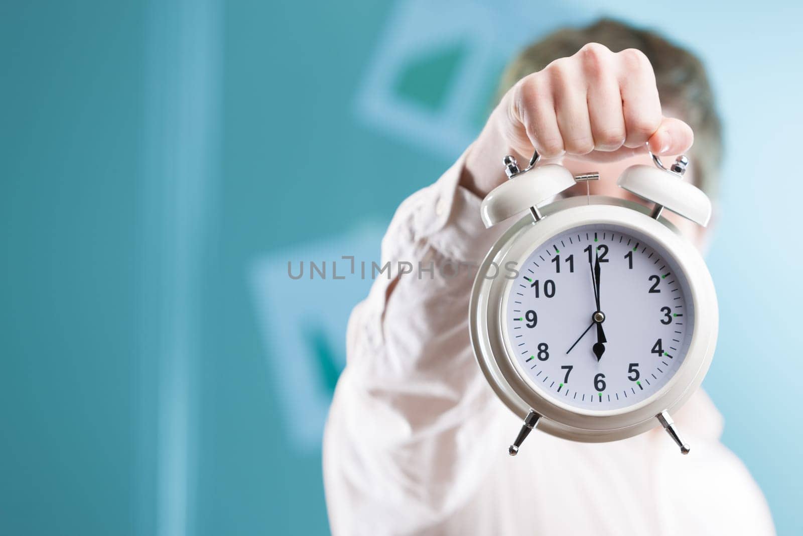 Against a blurry office backdrop, a hand extends a sizable clock. In the corporate world, time is invaluable, and deadlines are near. Stay nimble!