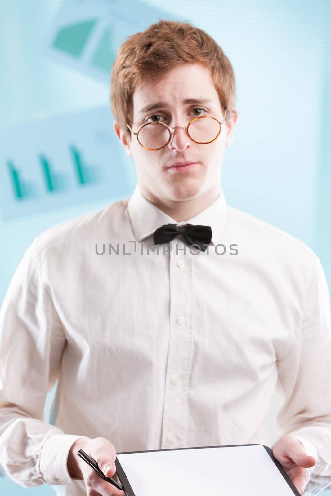 A somewhat nerdy, slightly subservient young man in a dated office suit, clutching a notepad, gazes sadly. His white shirt and bowtie suggest he may be an accountant