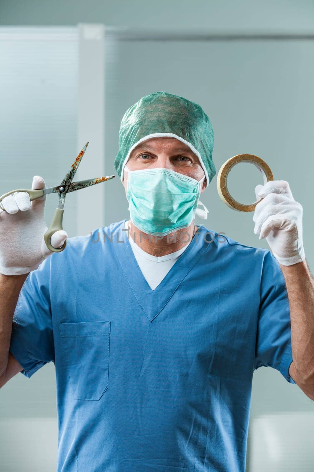 Surgeon in an operating room uses rusty scissors and paper tape. His ironic smile reveals the urgency for strict hospital tool regulation