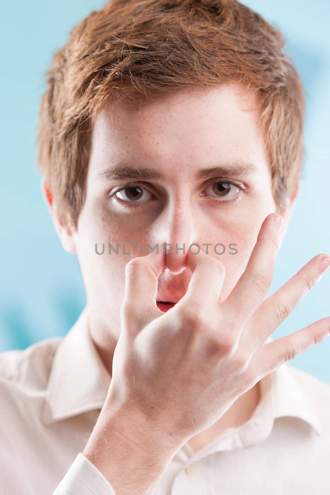 Red-haired office worker in a white shirt pinches his nose in distaste. Amid a blue business backdrop, he bears unethical practices to maintain his job