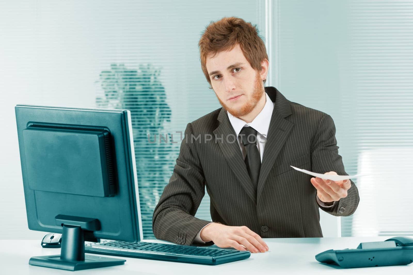 Young man hands you papers. Your employment contract or an important task to do? Sitting at his desk between keyboard and monitor and landline phone, he looks at you examining your reaction. Will you