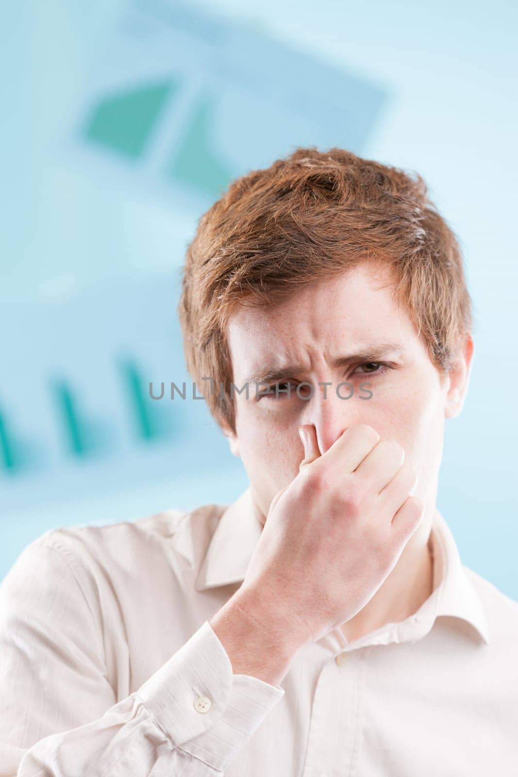 Young man with red hair, clad in a white office shirt, pinches his nose in displeasure. With a blue business backdrop, he's tolerating unsavory practices just to keep working
