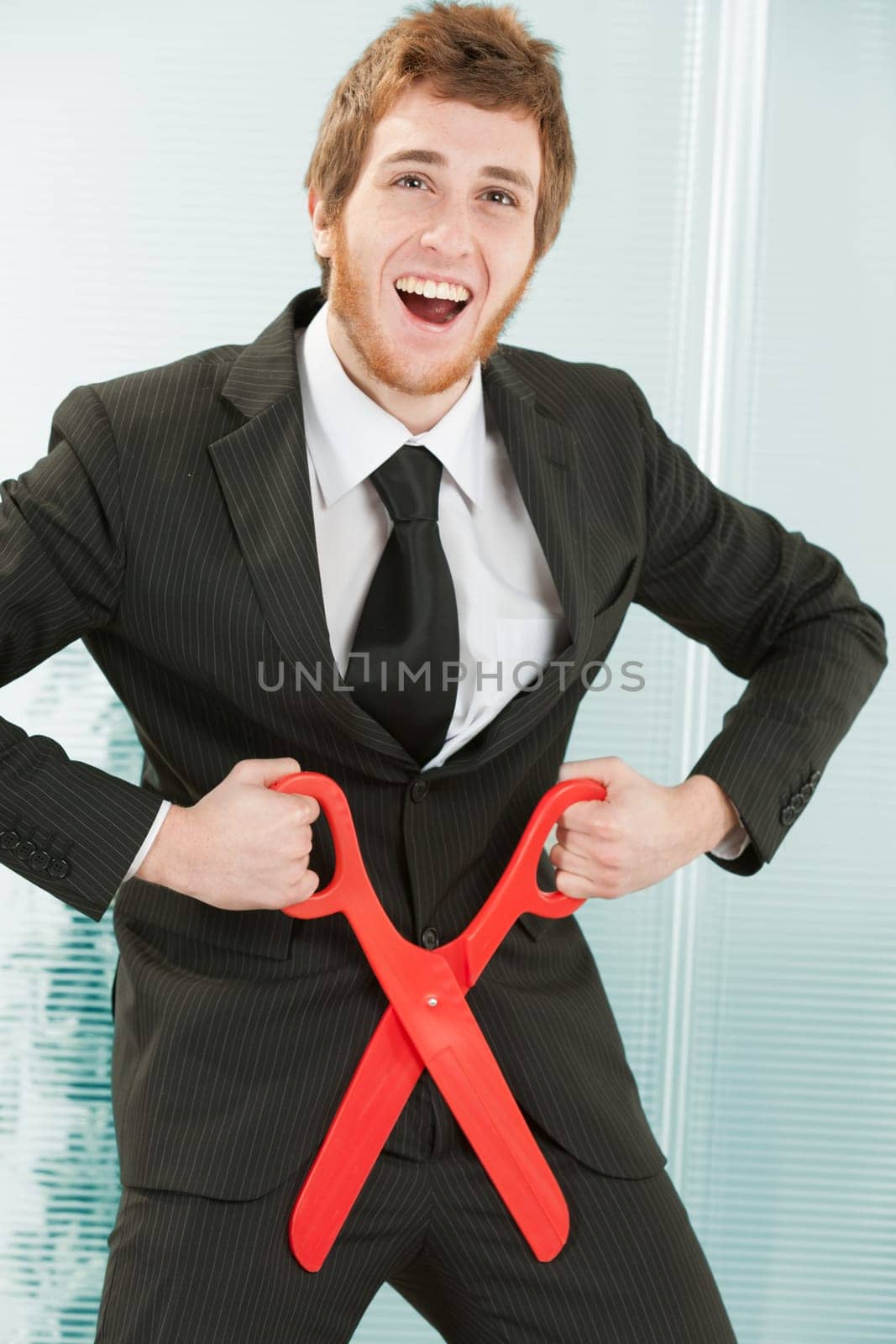 young businessman in a manga or anime attitude with a somewhat dumb and somewhat crazy, amused expression makes the gesture of cutting off his penis. Humorous depiction of self-sabotage.