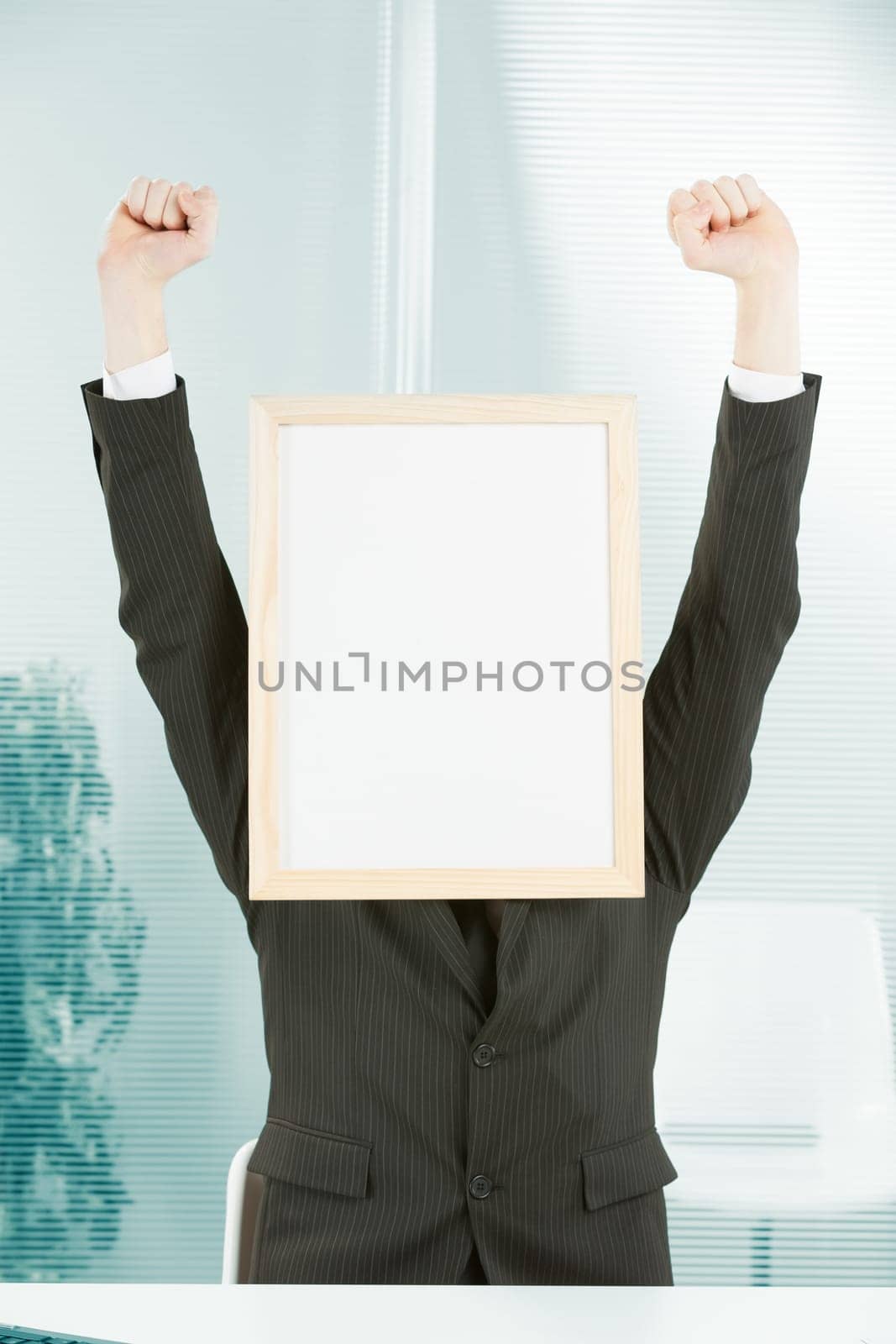 Businessman with sign head and hands raised in jubilation. There is great enthusiasm at the workplace for the light-wood framed COPYSPACE.