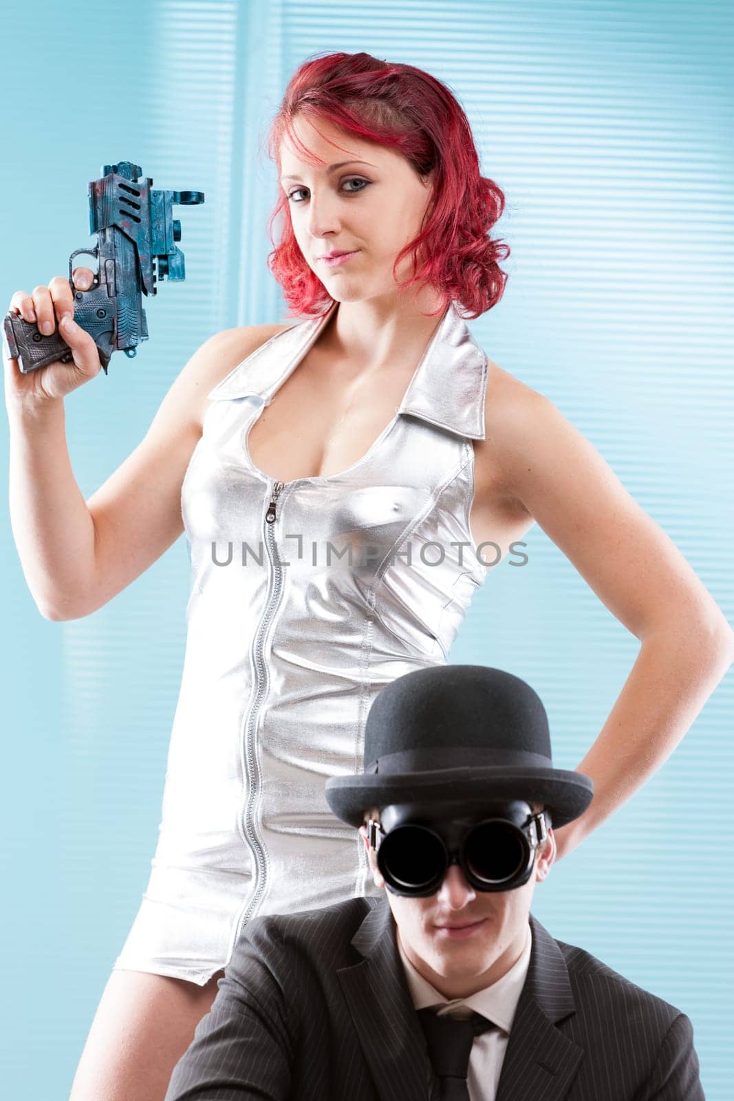 Blending steampunk and '60s sci-fi aesthetics, two superheroes emerge. The woman in silver with fiery hair the man in chic black, bowler hat, and shades. Set against a modern blue scene, they're read