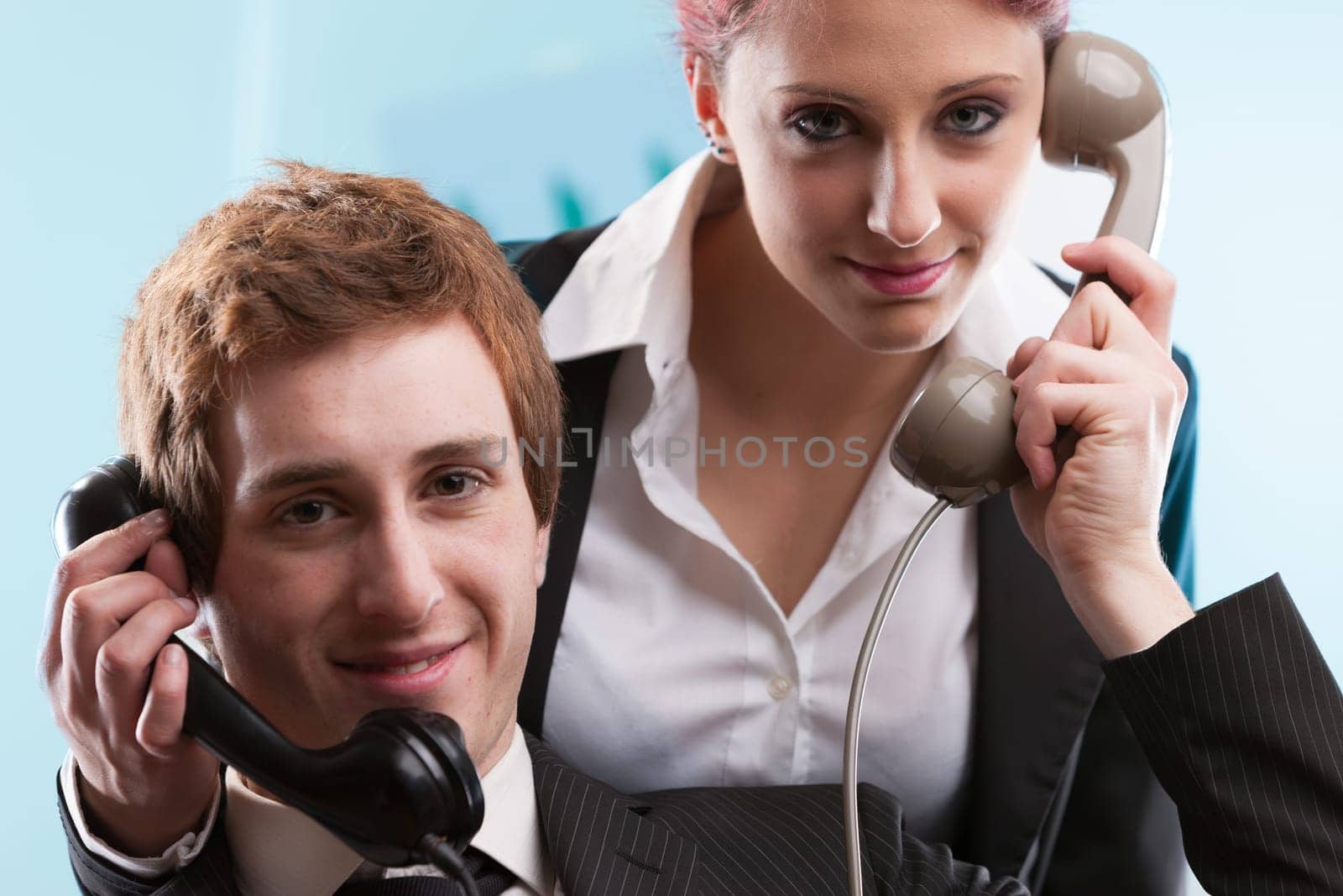 Man and woman in business attire manage high-stress calls in a bustling customer service center