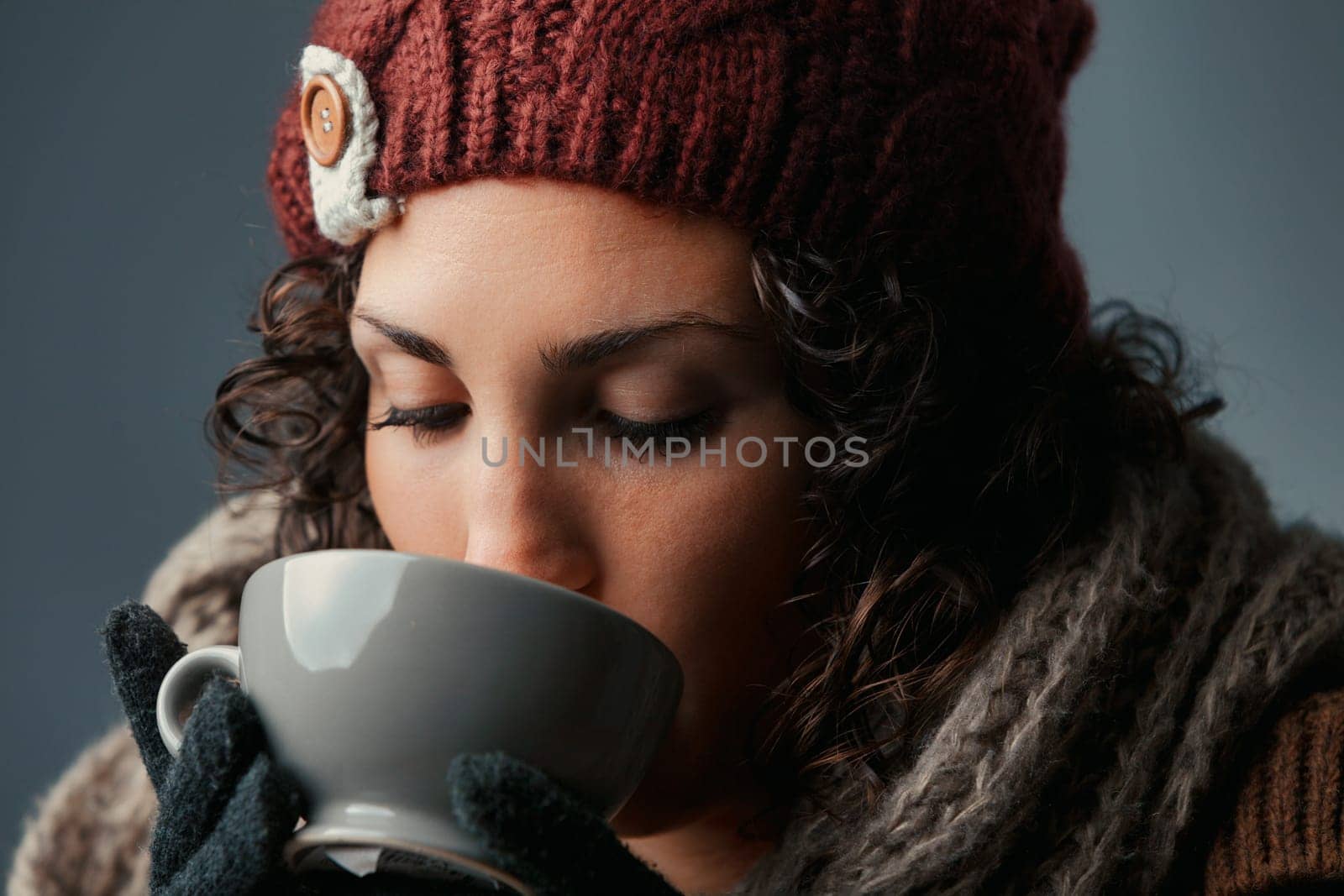 Wrapped in winter wear, a youthful female savors a comforting drink, maybe hot chocolate or café latte. From a mountain shelter or town café, her animated eyes tell stories of her day ahead