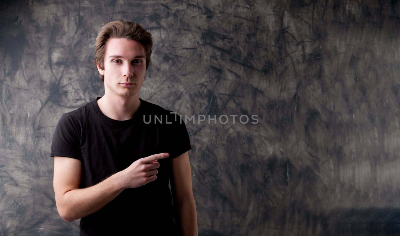 Trust this young academic in front of a dark board, pointing to a large copyspace. He signifies rigorous scientific methods and discussions within a dedicated community